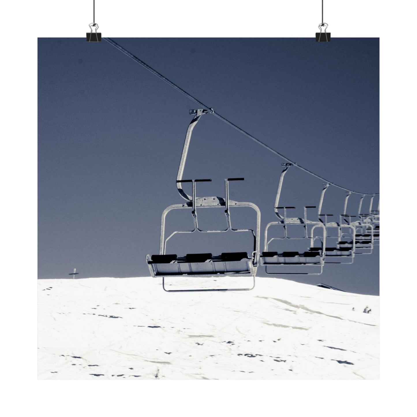 Ski lift chairs on a snowy mountain with clear blue sky