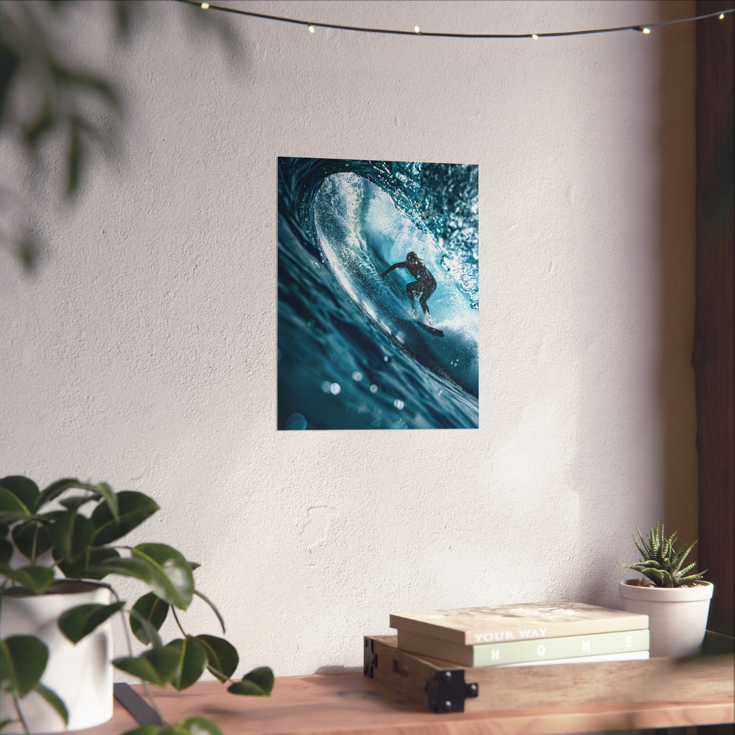Poster of a surfer on a wave hanging on a wall above a wooden shelf with plants and books.