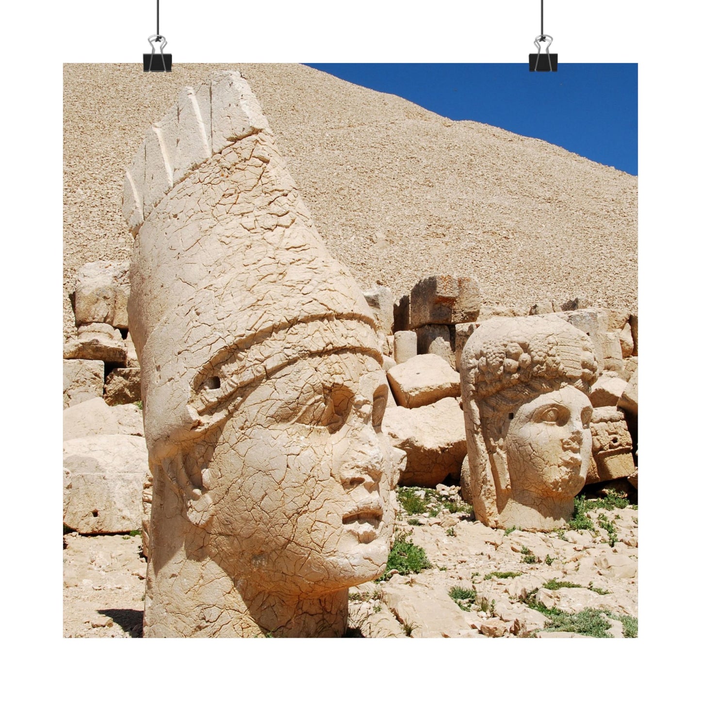 Stone heads of ancient statues on a rocky hillside with a clear blue sky.