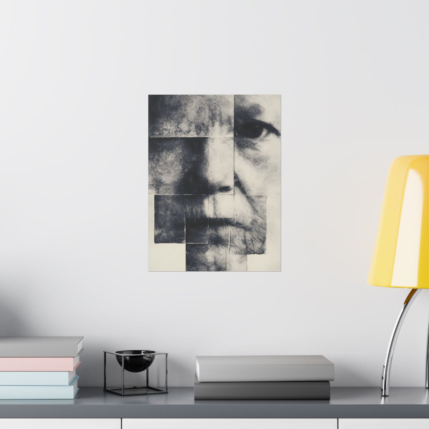 Abstract art piece on a wall above a desk with books and a lamp.