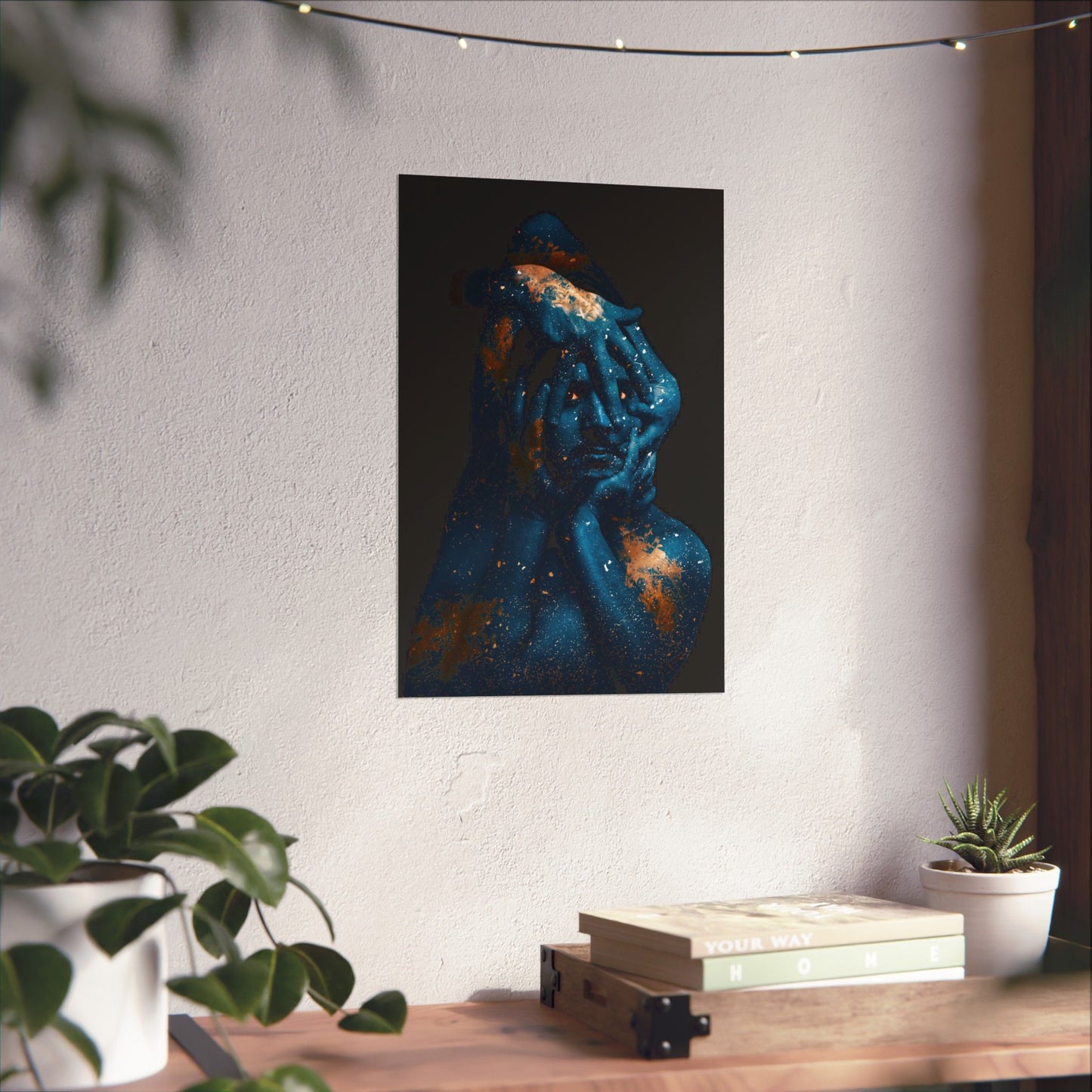 Abstract art piece on a wall above a wooden table with plants and books.