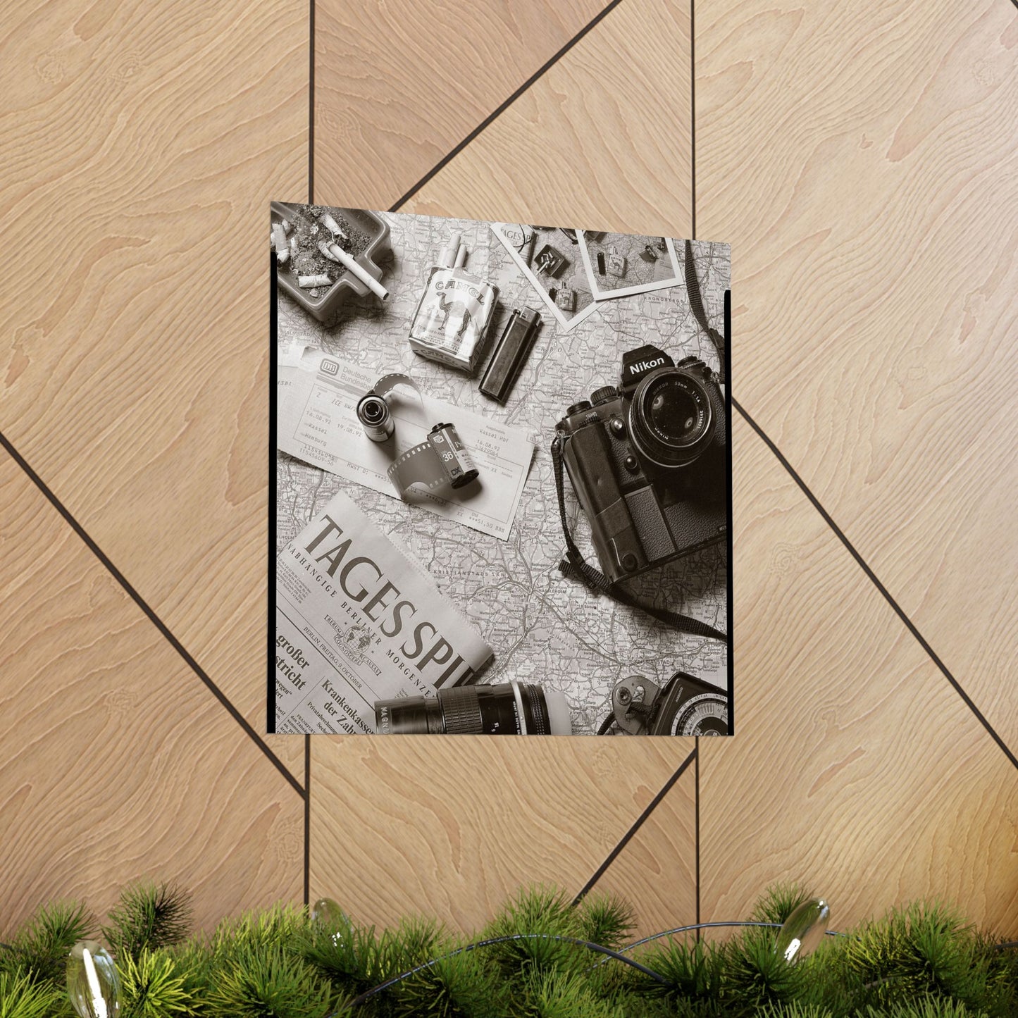 Framed photo of a camera and vintage items on a map with 'Tagespiegel' text, on a wooden floor.