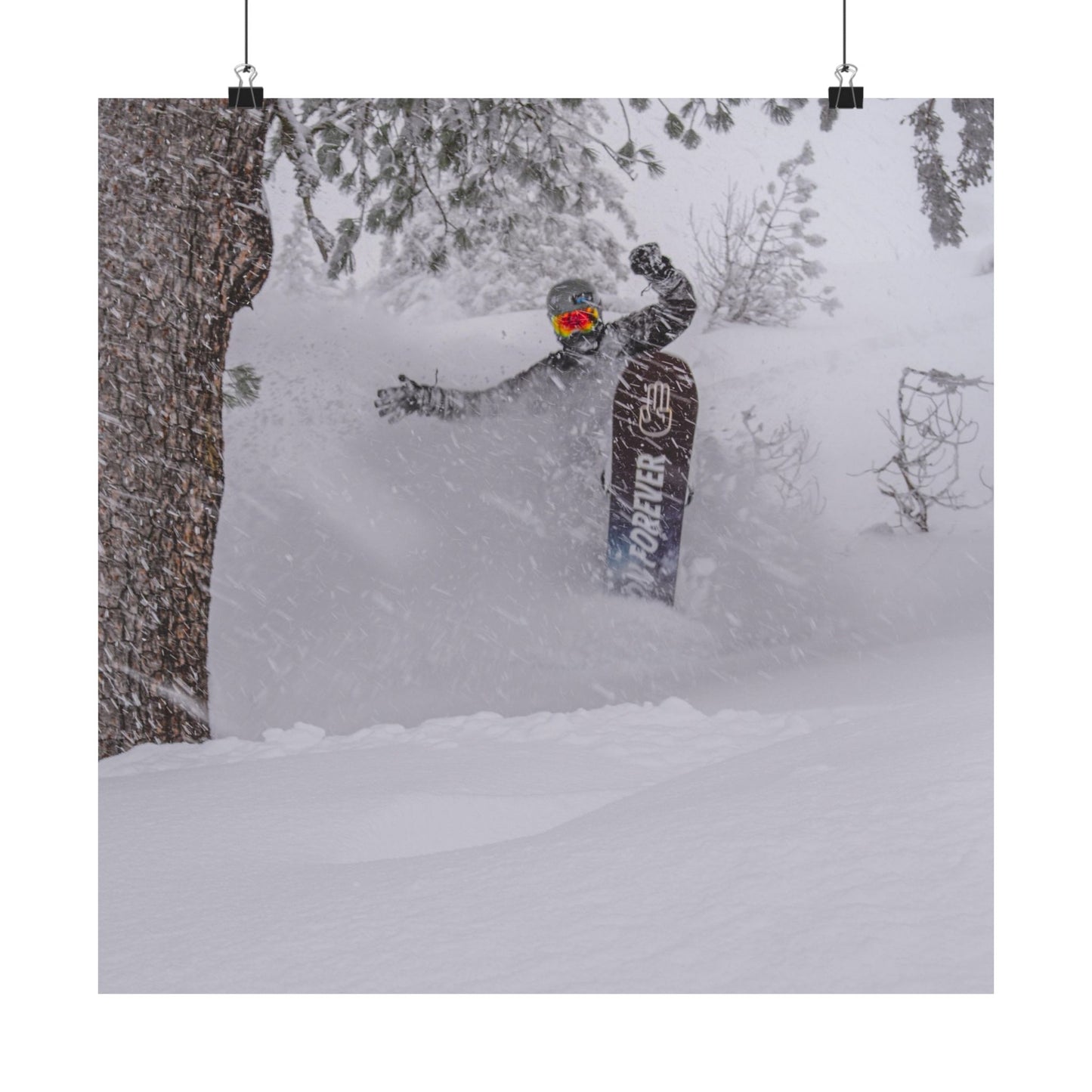 Person snowboarding in a snowy forest with a snowboard featuring the brand 'Burton'.