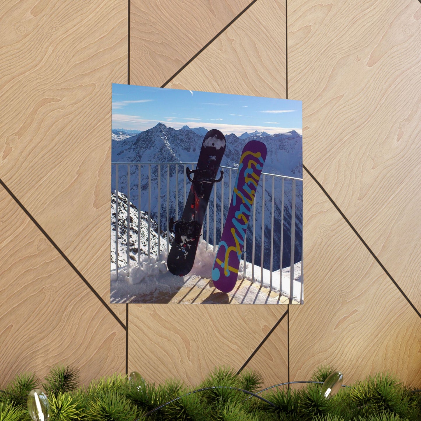 Two snowboards against a mountainous backdrop on a wooden surface.