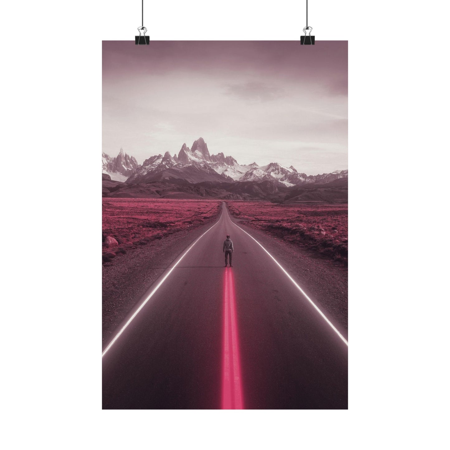 Person standing in the middle of a road with a pink glow, leading towards snow-capped mountains.