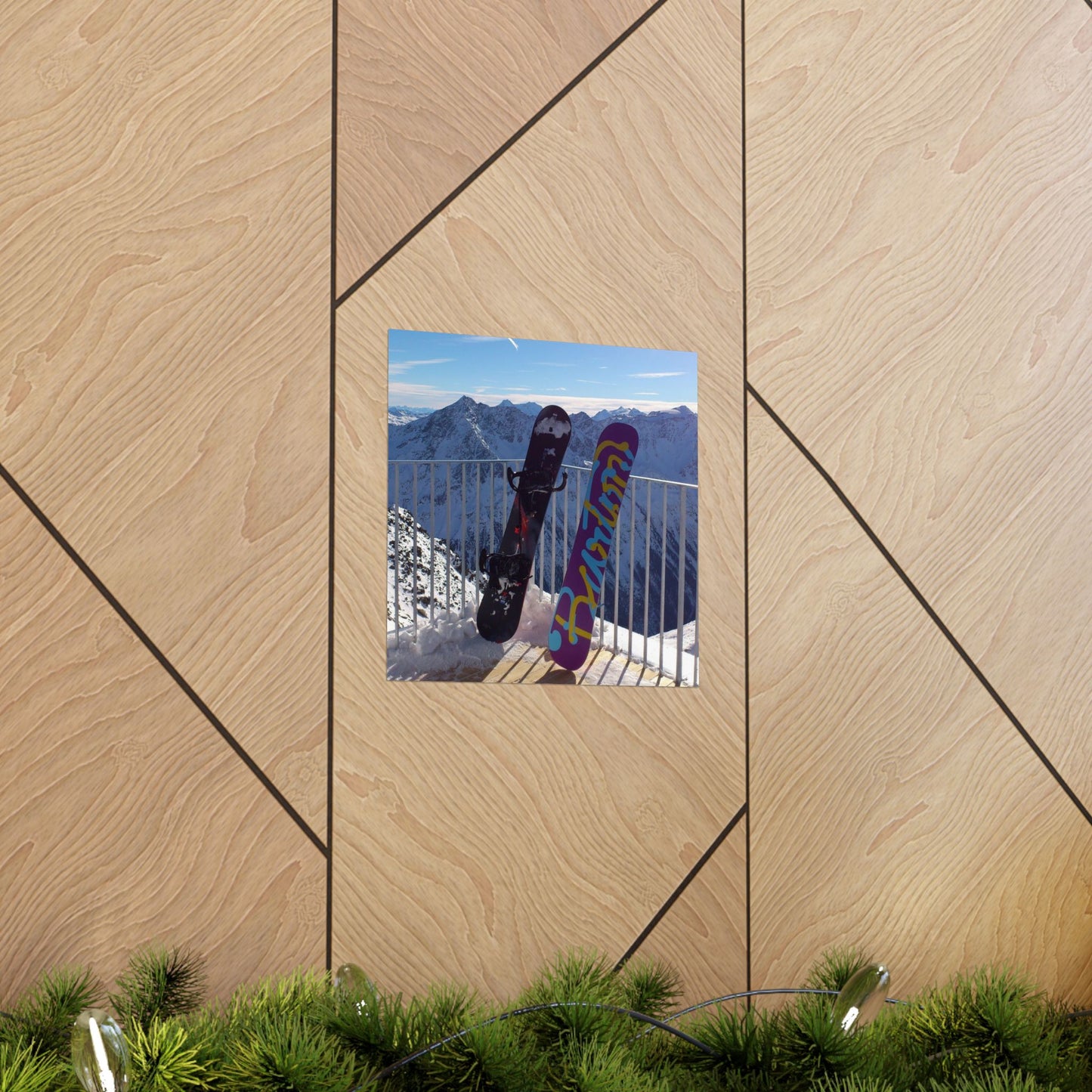 Decorative wall art with a mountain scene and snowboards on a wooden panel background.