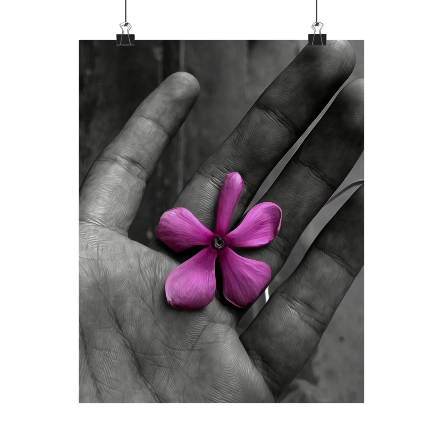 Purple flower held between two hands, with a black and white background