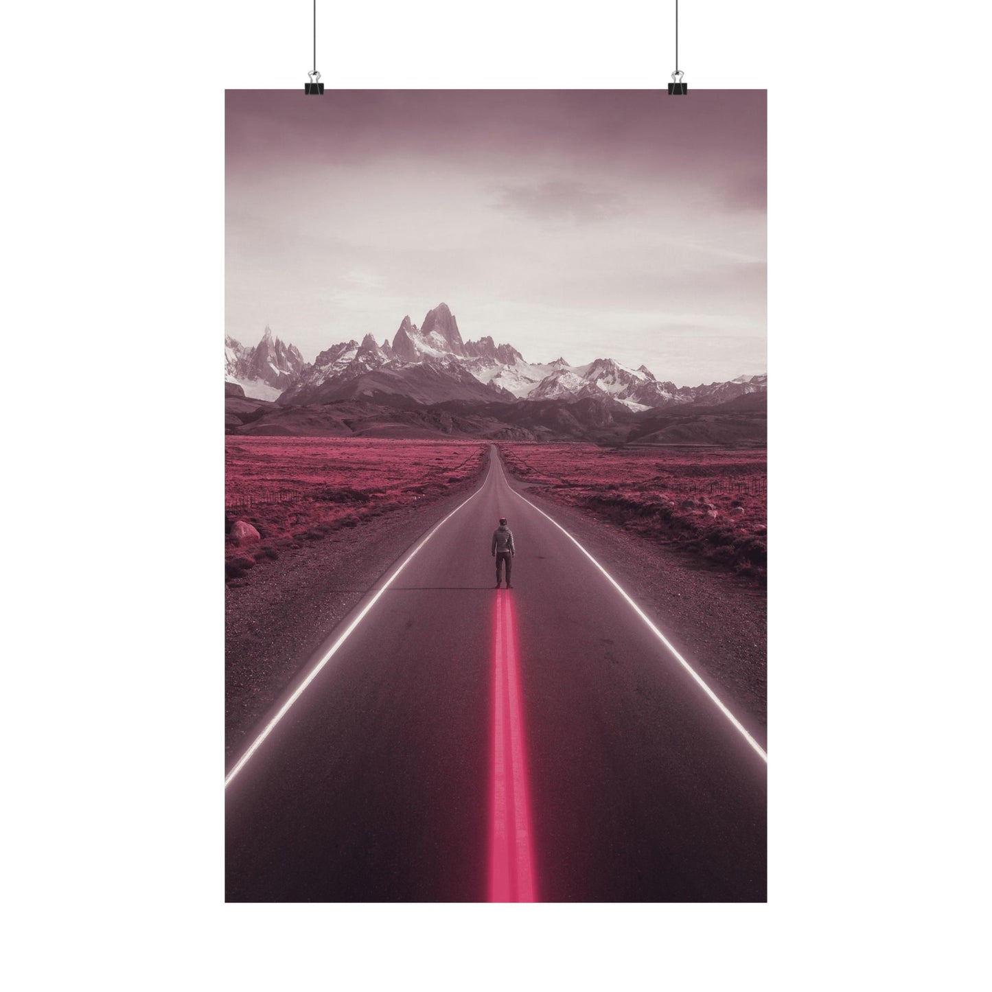 Person standing in the middle of a road with a pink glow, leading towards snow-capped mountains.