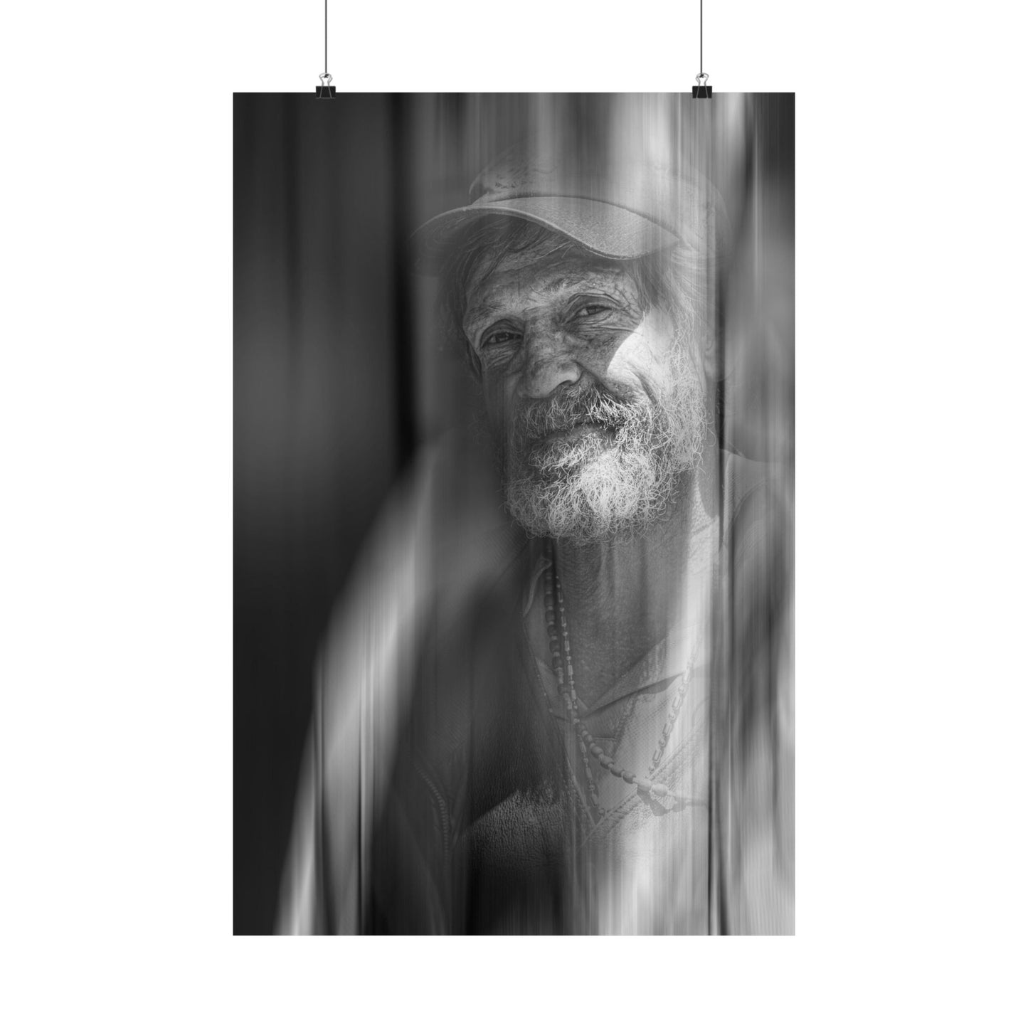 Black and white portrait of a man with a cap and beard, hanging on a white wall.