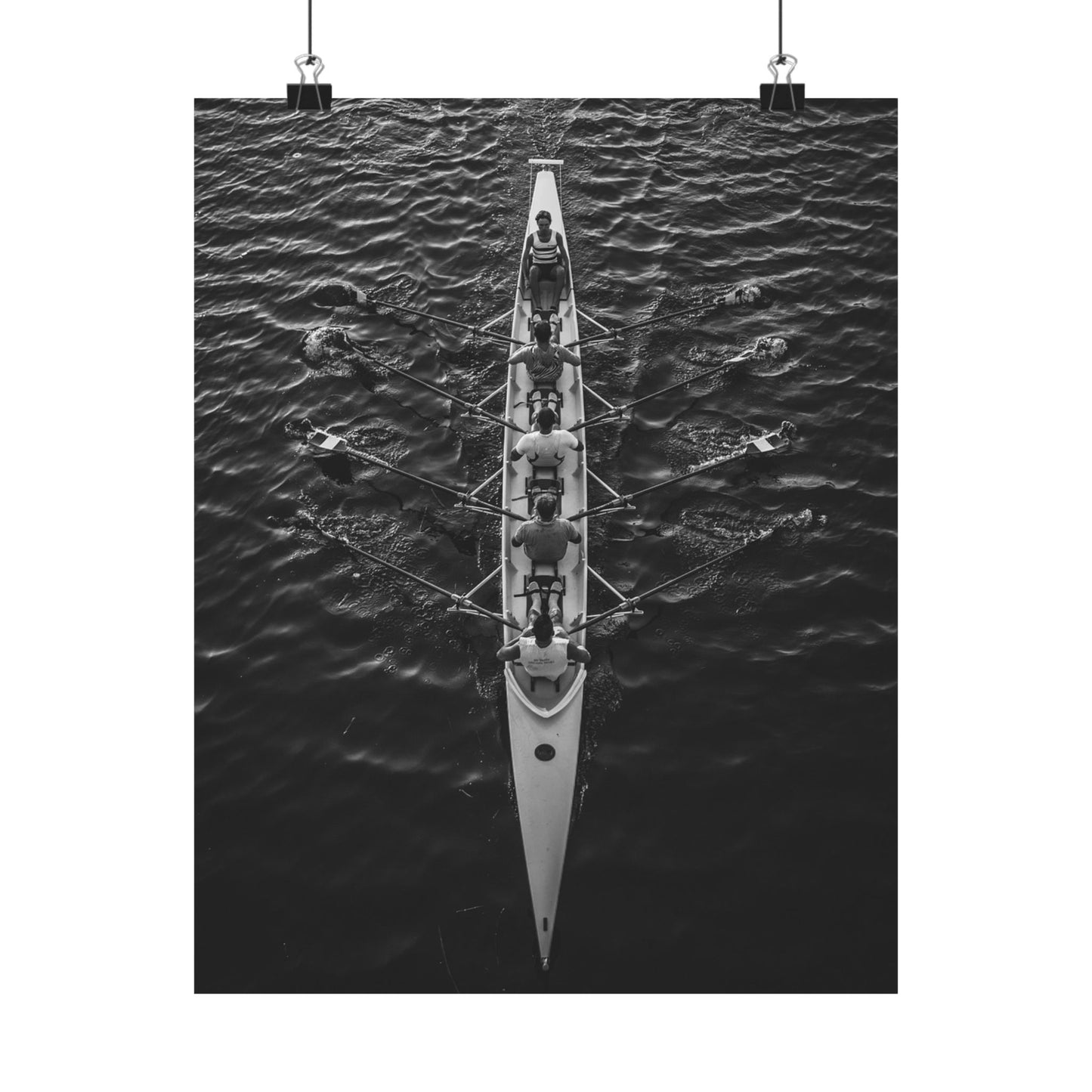 Black and white image of a rowing boat with rowers on water