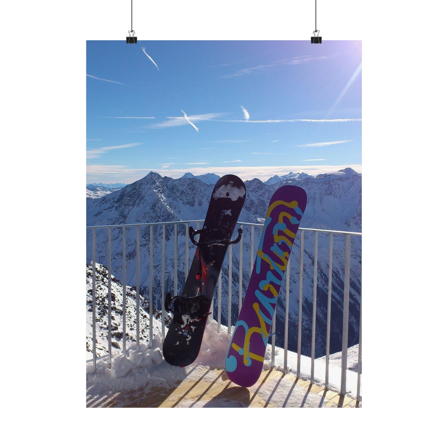 Two snowboards against a mountainous landscape with a clear blue sky.