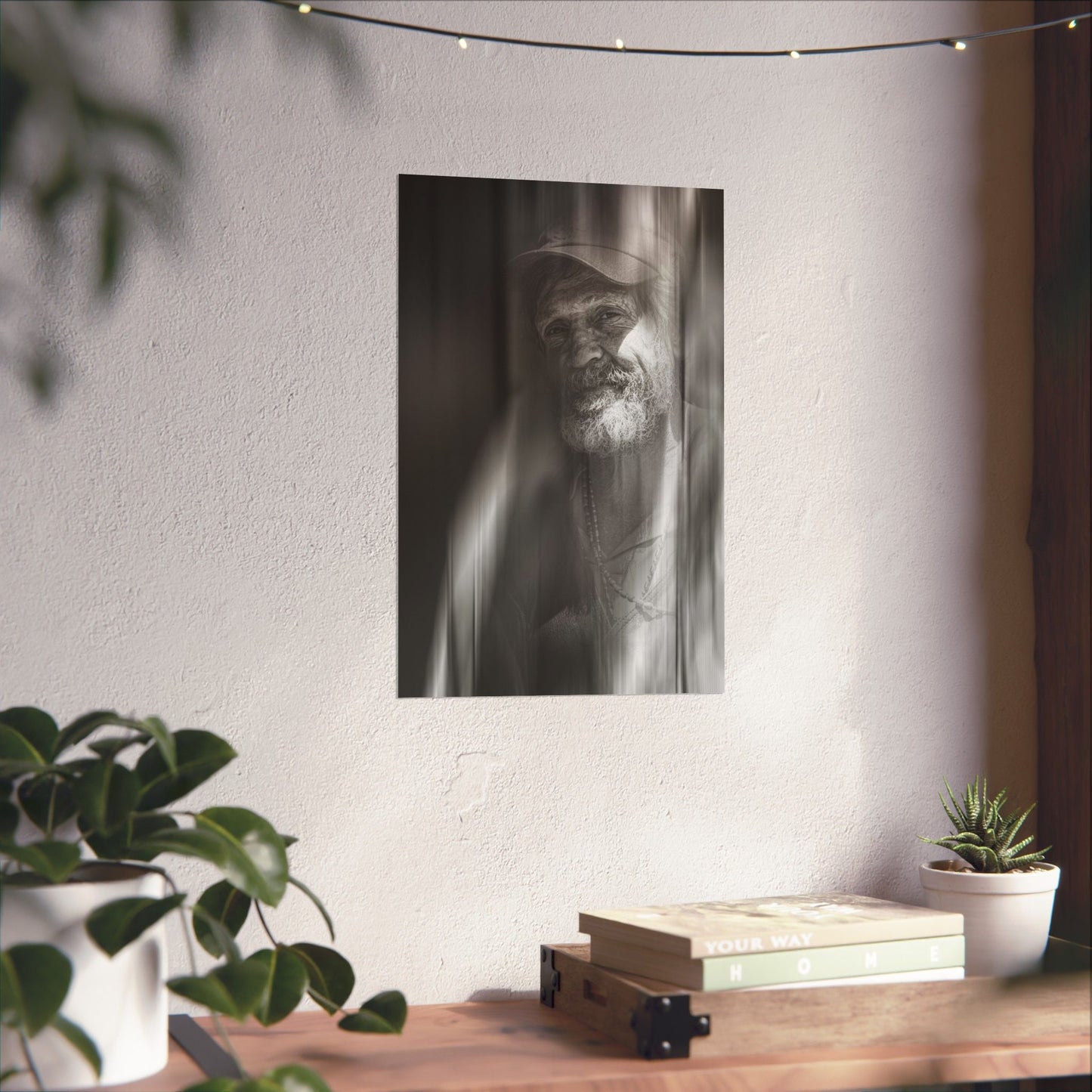 Poster of a man with a beard on a wall above a wooden shelf with books and plants.
