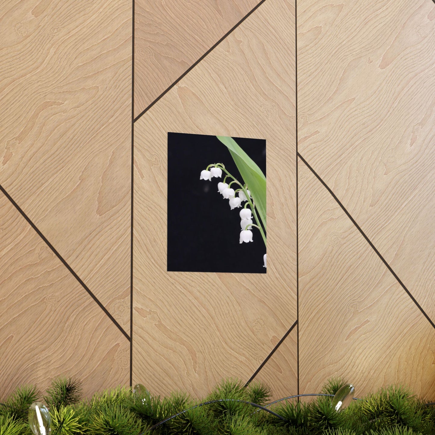 Framed picture of flowers on a wooden wall with greenery at the bottom.