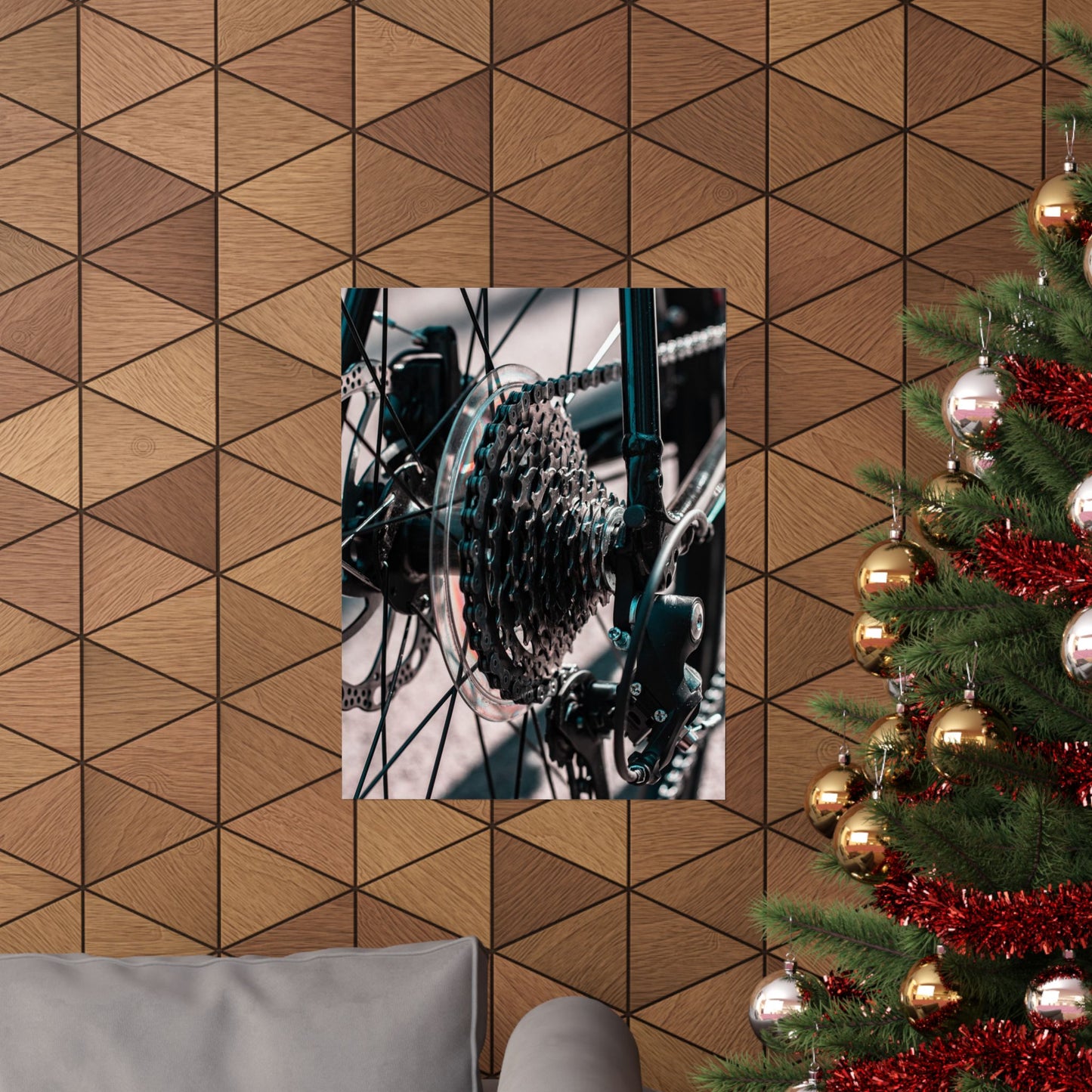 Close-up of a bicycle gear system on a geometric-patterned wall with a Christmas tree to the right.