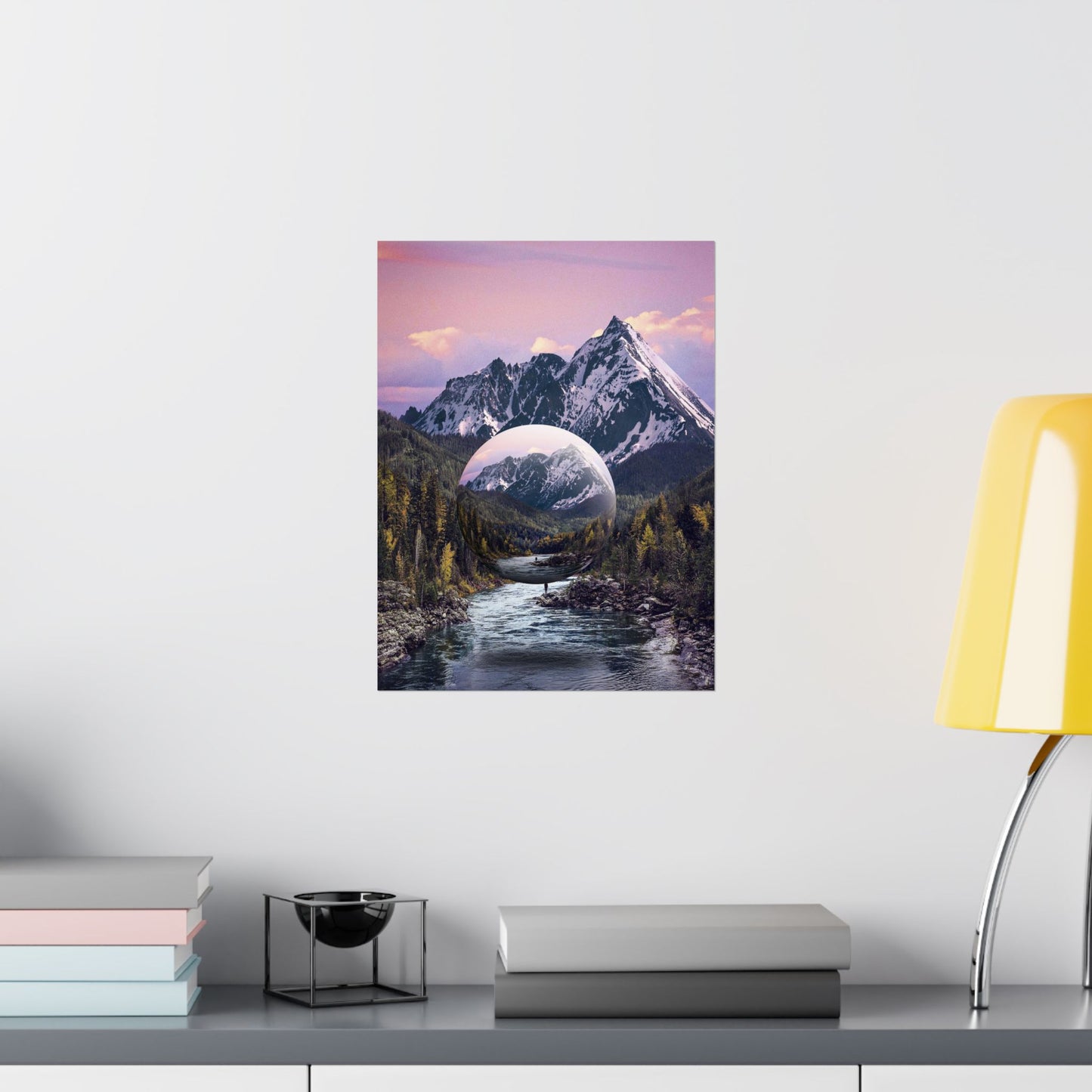 Framed artwork of a mountain landscape with a river and a large moon on a white wall.