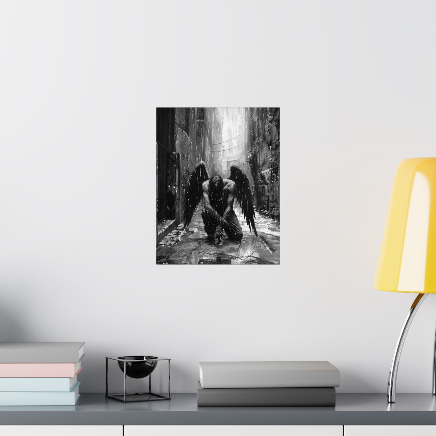 Framed artwork of two angelic figures in a dark, gothic setting on a white wall above a shelf.