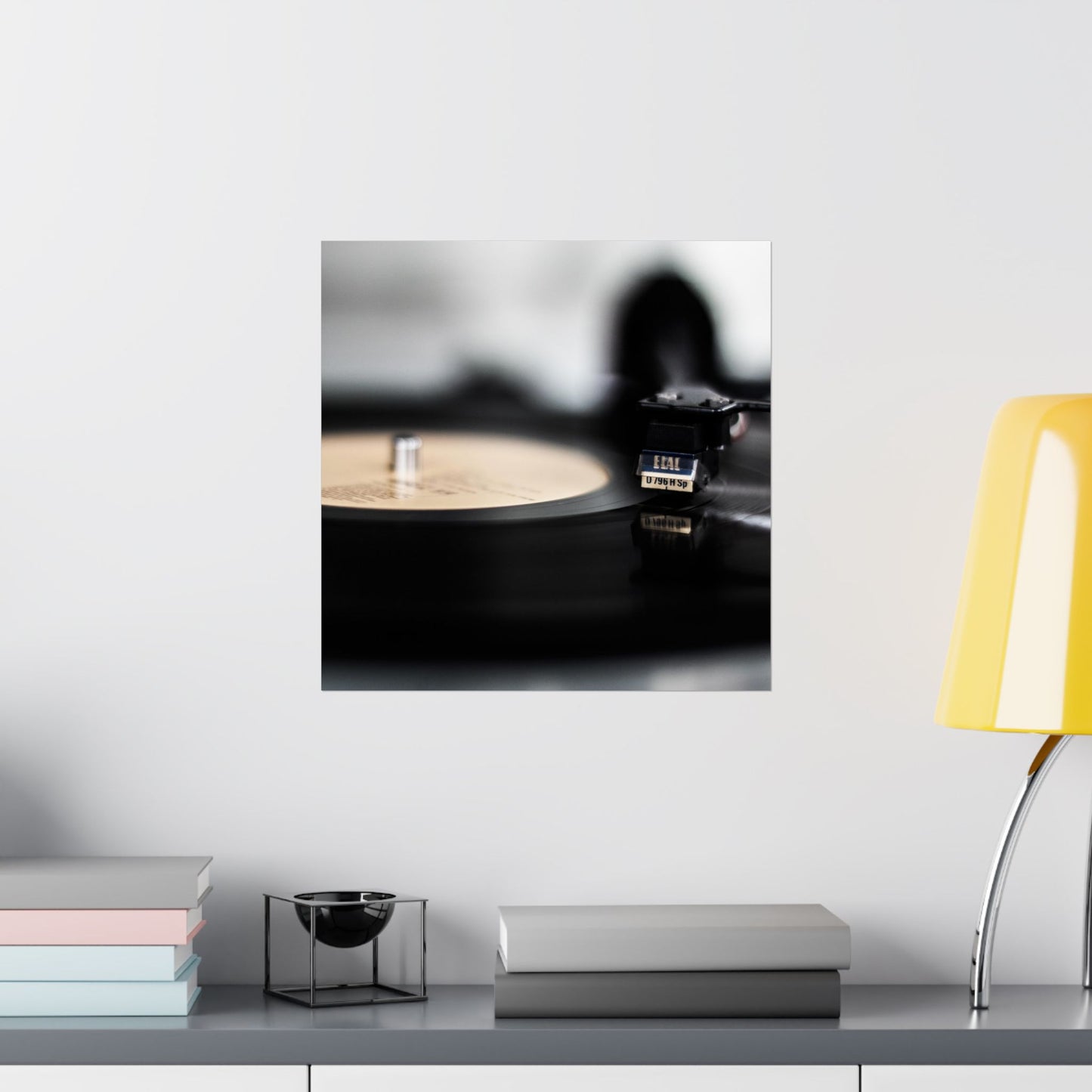 Framed picture of a vinyl record player on a shelf with books and a lamp.