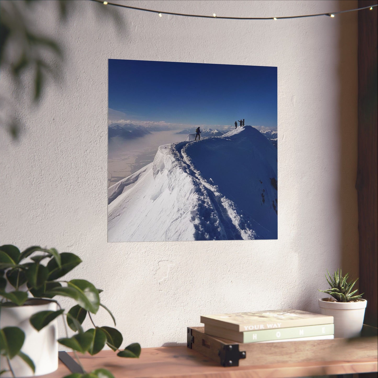 Poster of a snowy mountain landscape on a wall above a desk with plants and books.