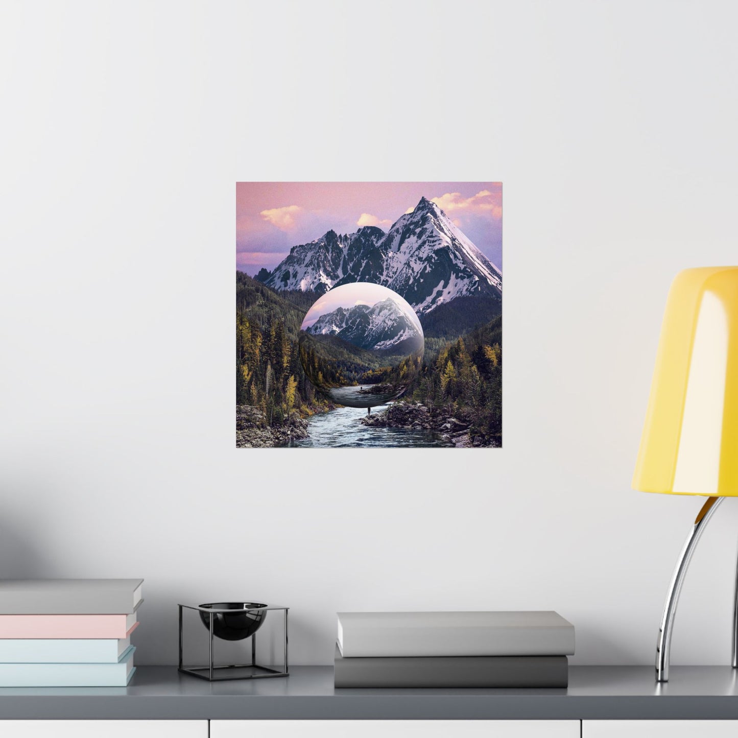 Framed artwork of a mountain landscape with a reflective surface on a wall above a shelf.
