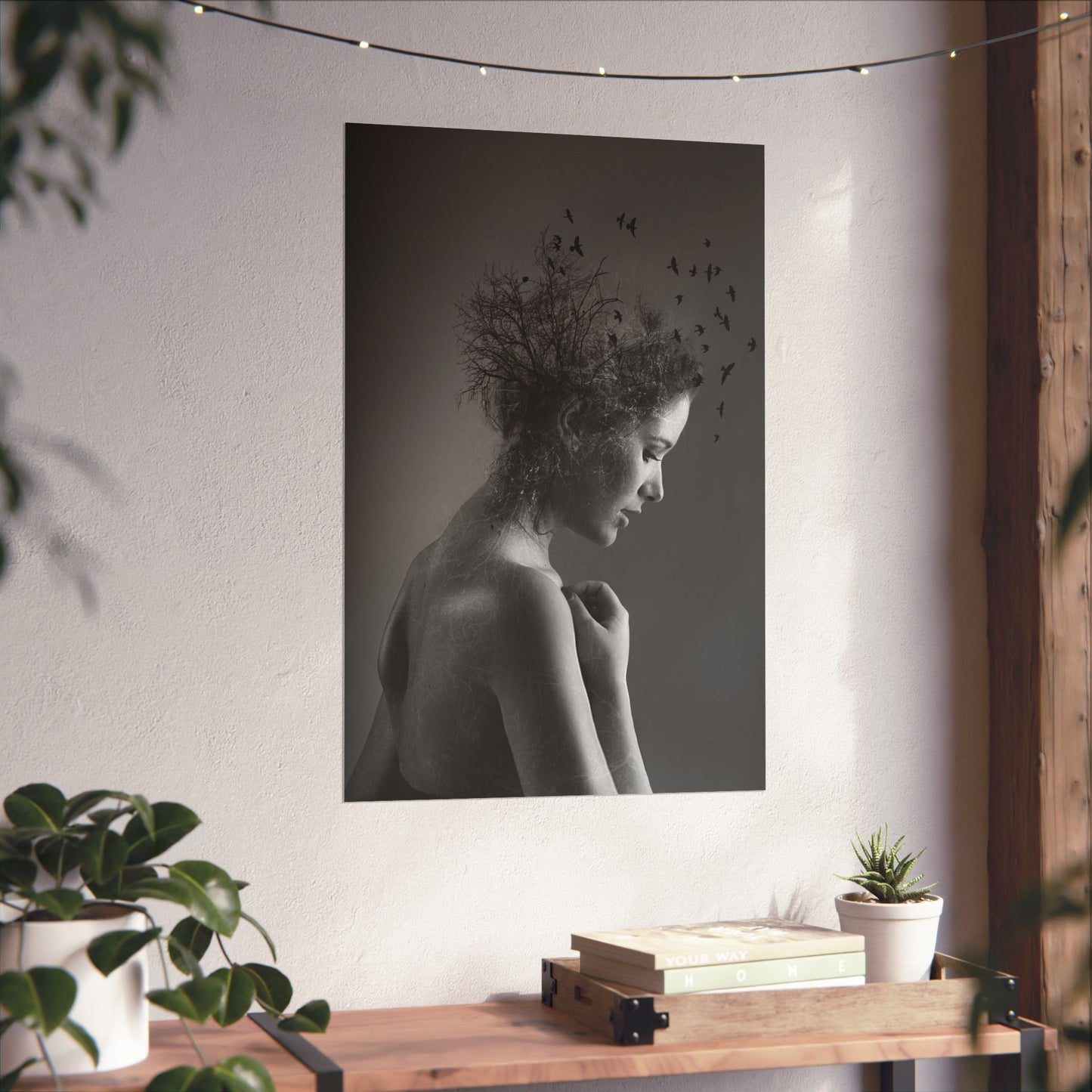 Framed black and white portrait of a woman with nature elements on a wall above a wooden console table.