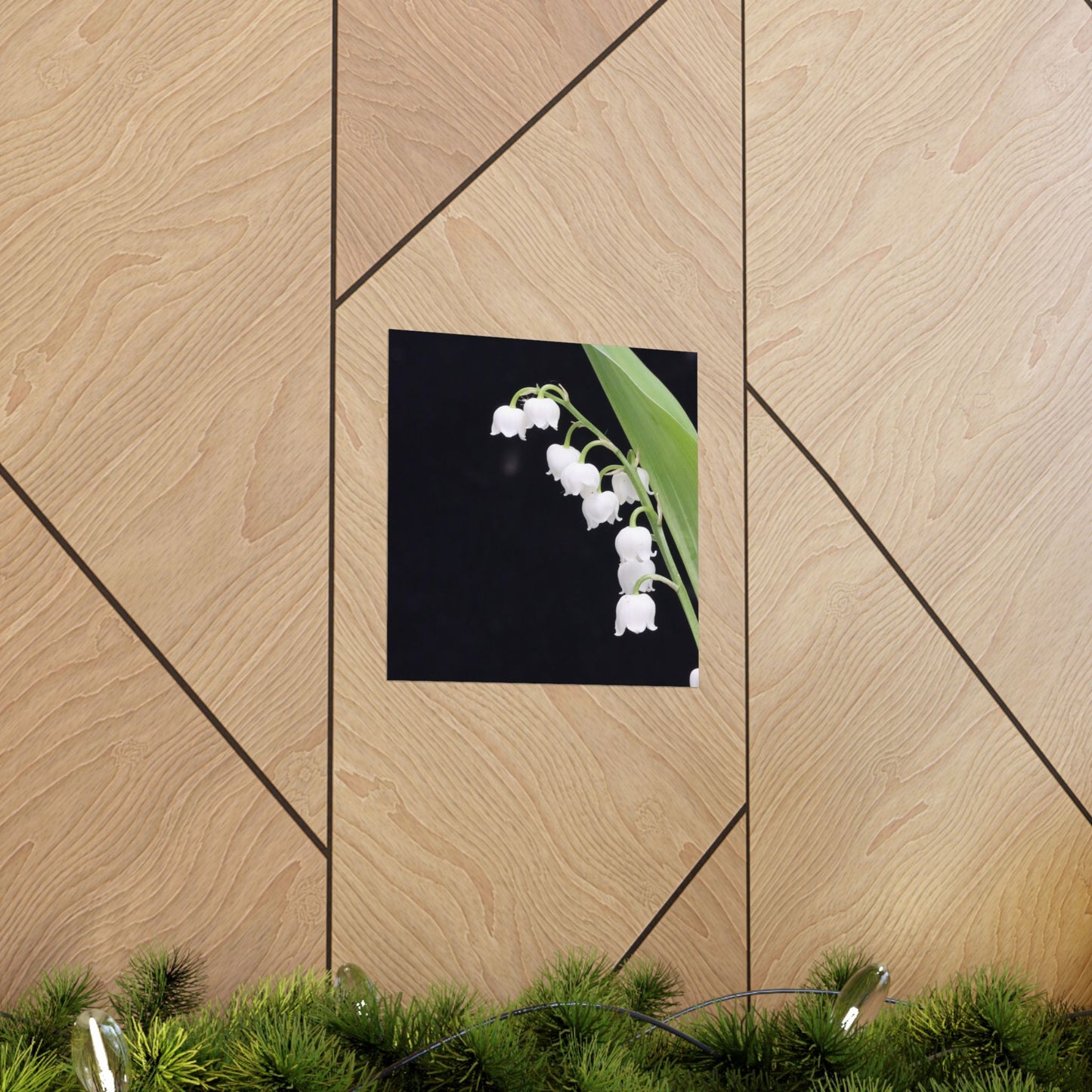 Framed picture of white flowers on a wooden wall with greenery at the bottom.