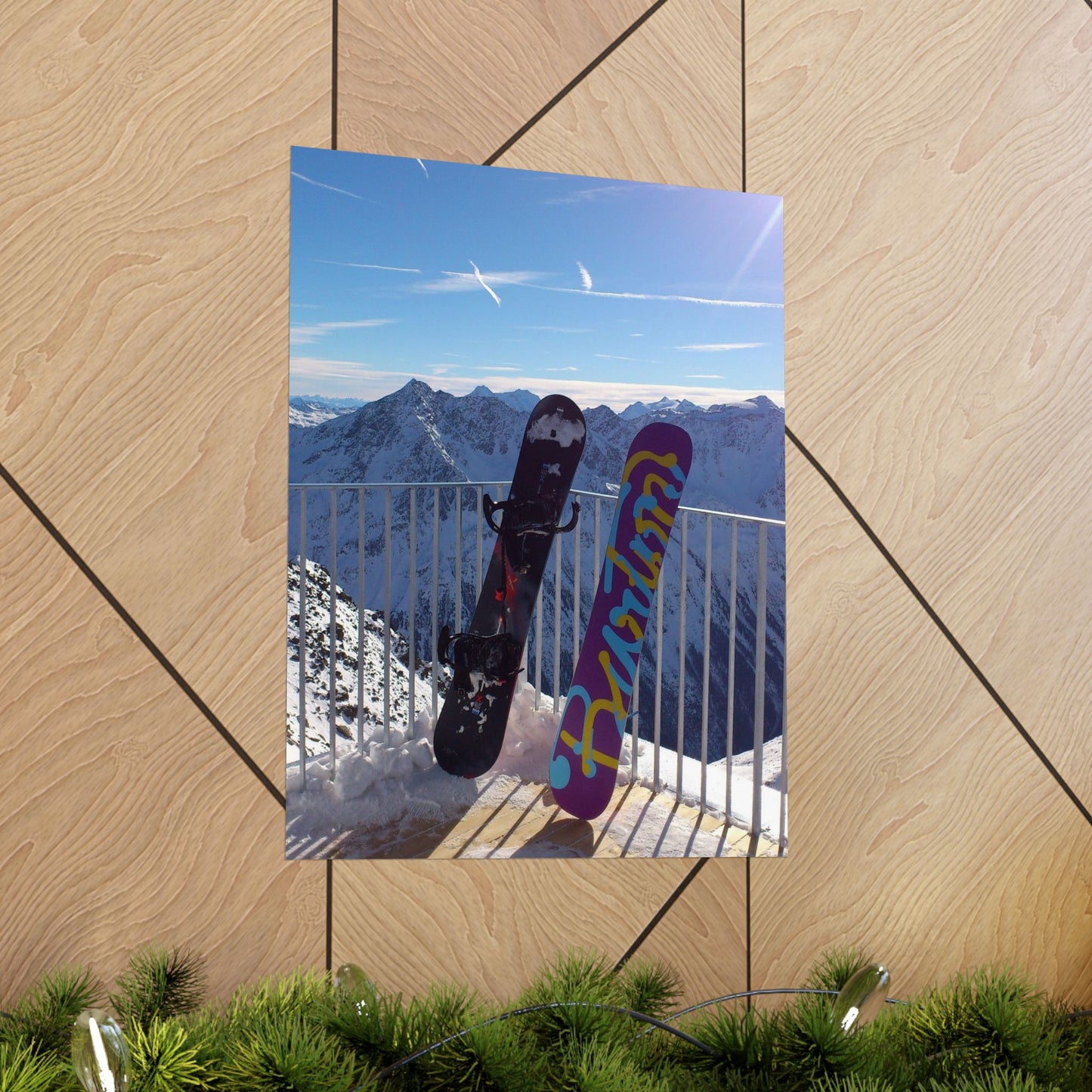 Two snowboards with colorful designs leaning against a railing with a mountain view in the background.