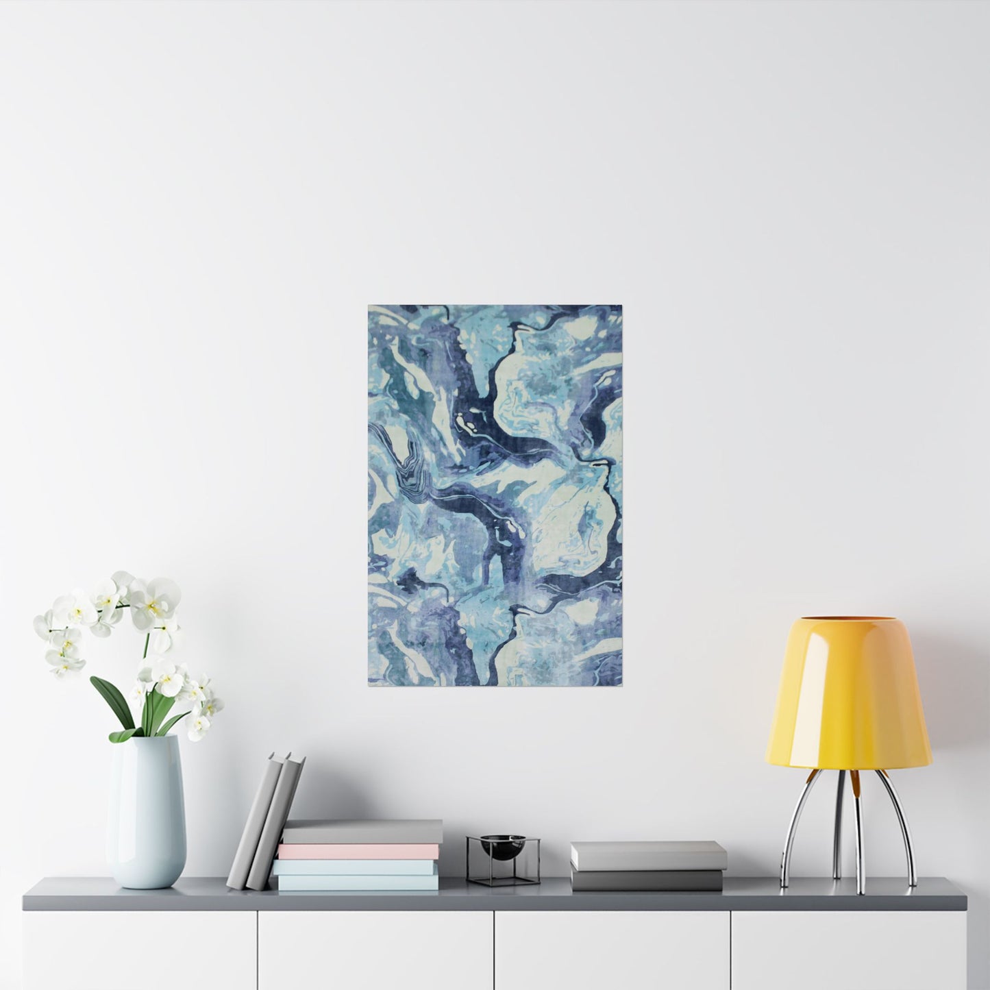 Abstract blue and white painting on a wall above a shelf with decor items.