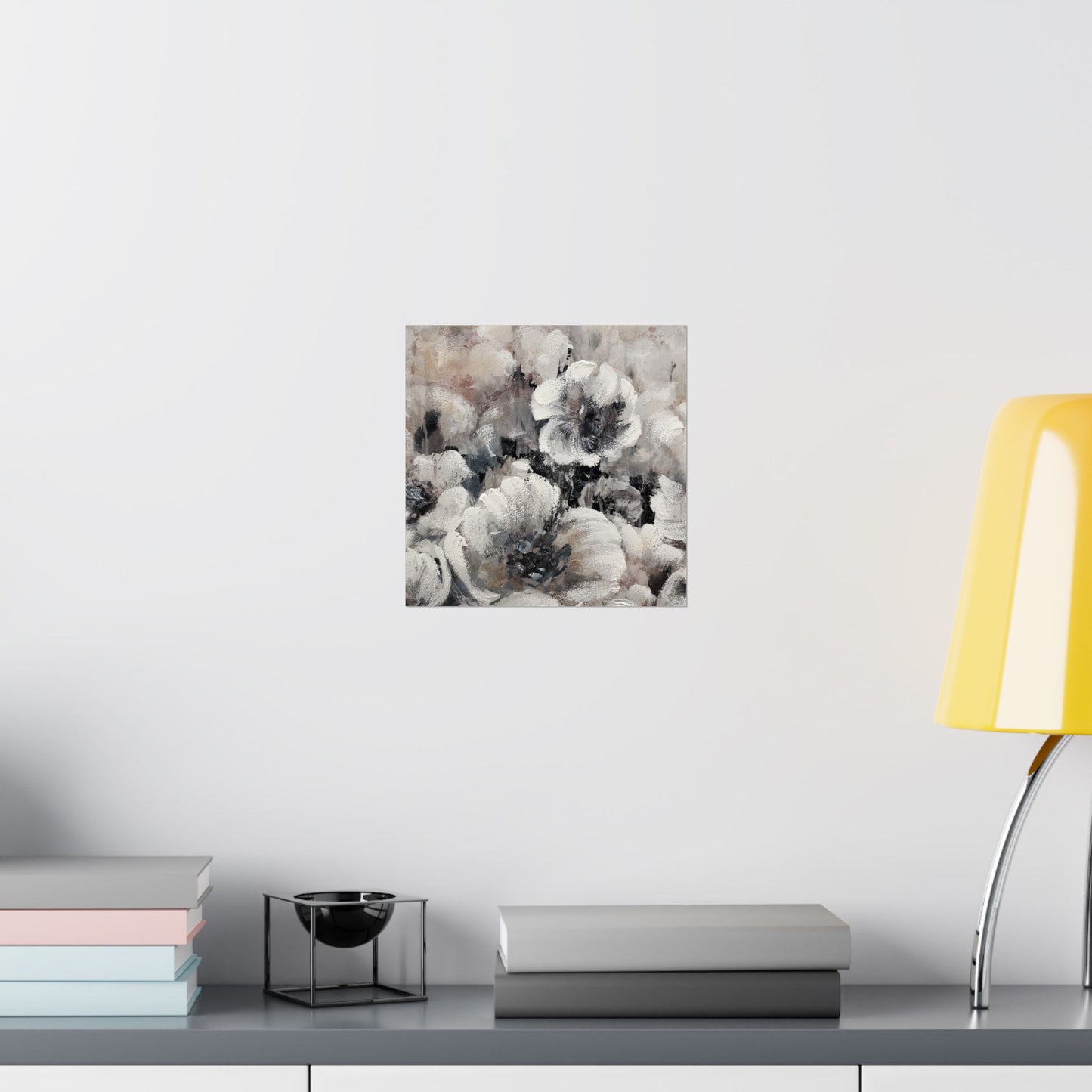 Floral painting on a wall above a table with books and a lamp.