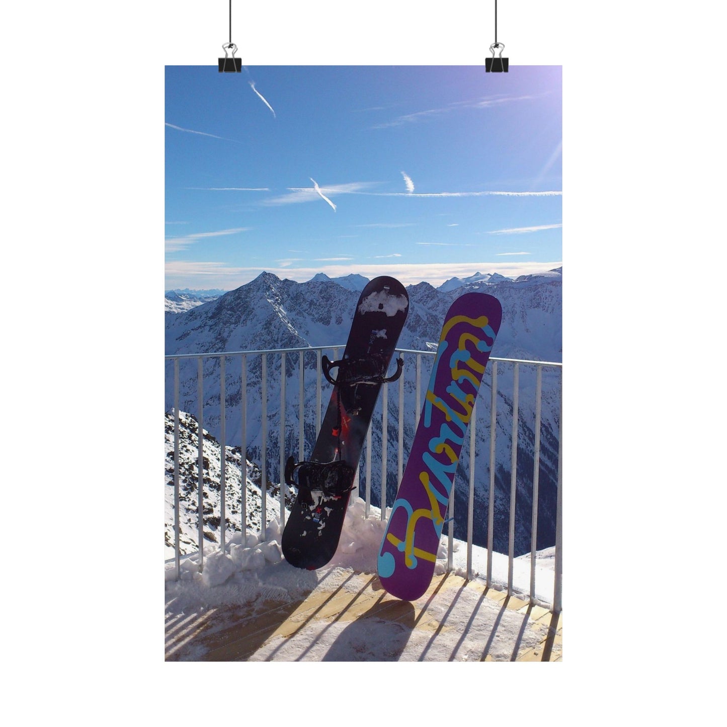 Two snowboards against a mountainous landscape with a clear blue sky.