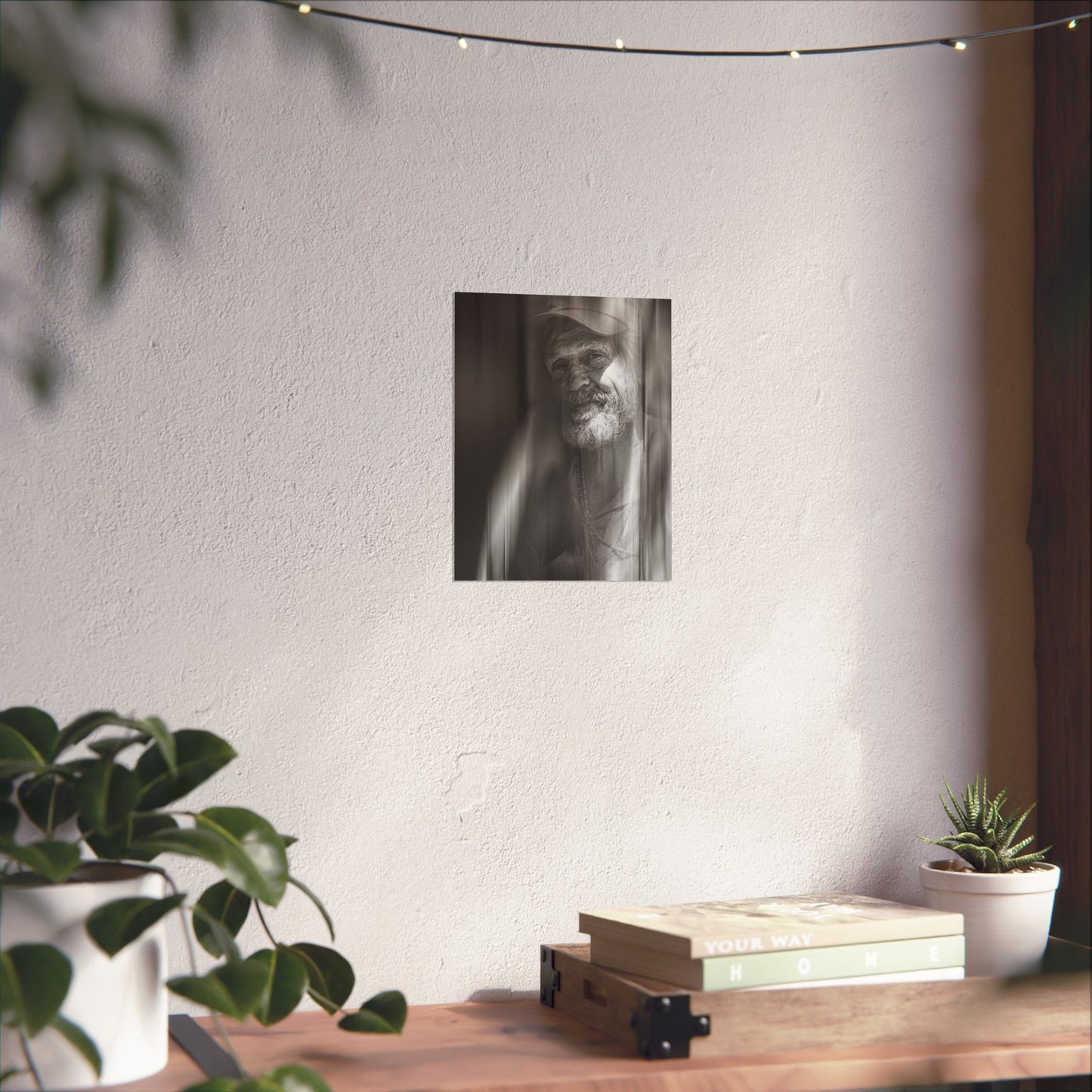 Poster of a bearded man on a wall above a wooden shelf with books and plants.