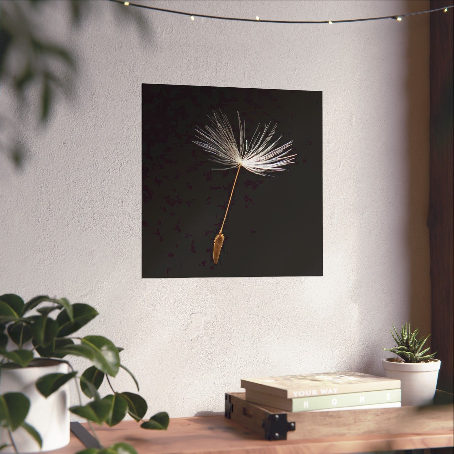 Dandelion seed head artwork on a wall with plants and books below