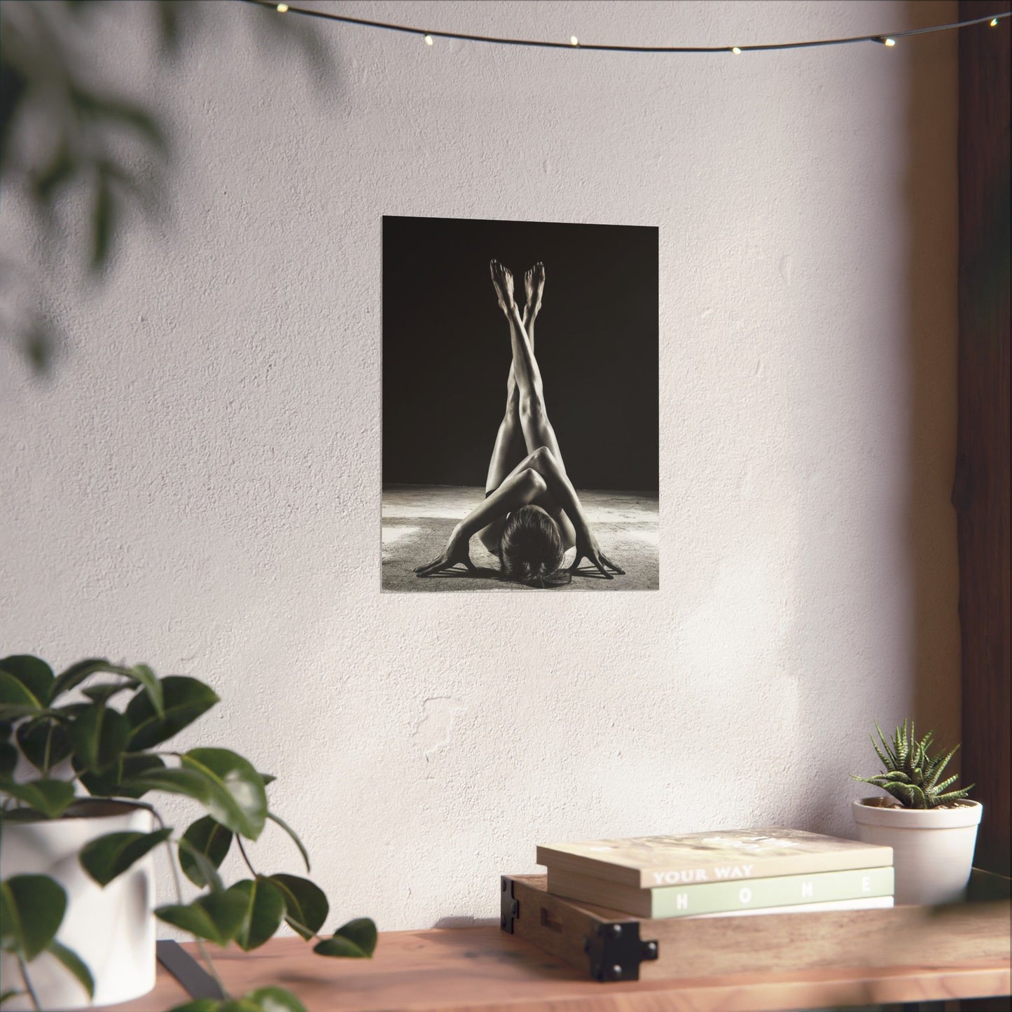 Poster of a person in a yoga pose on a wall above a desk with plants and books.