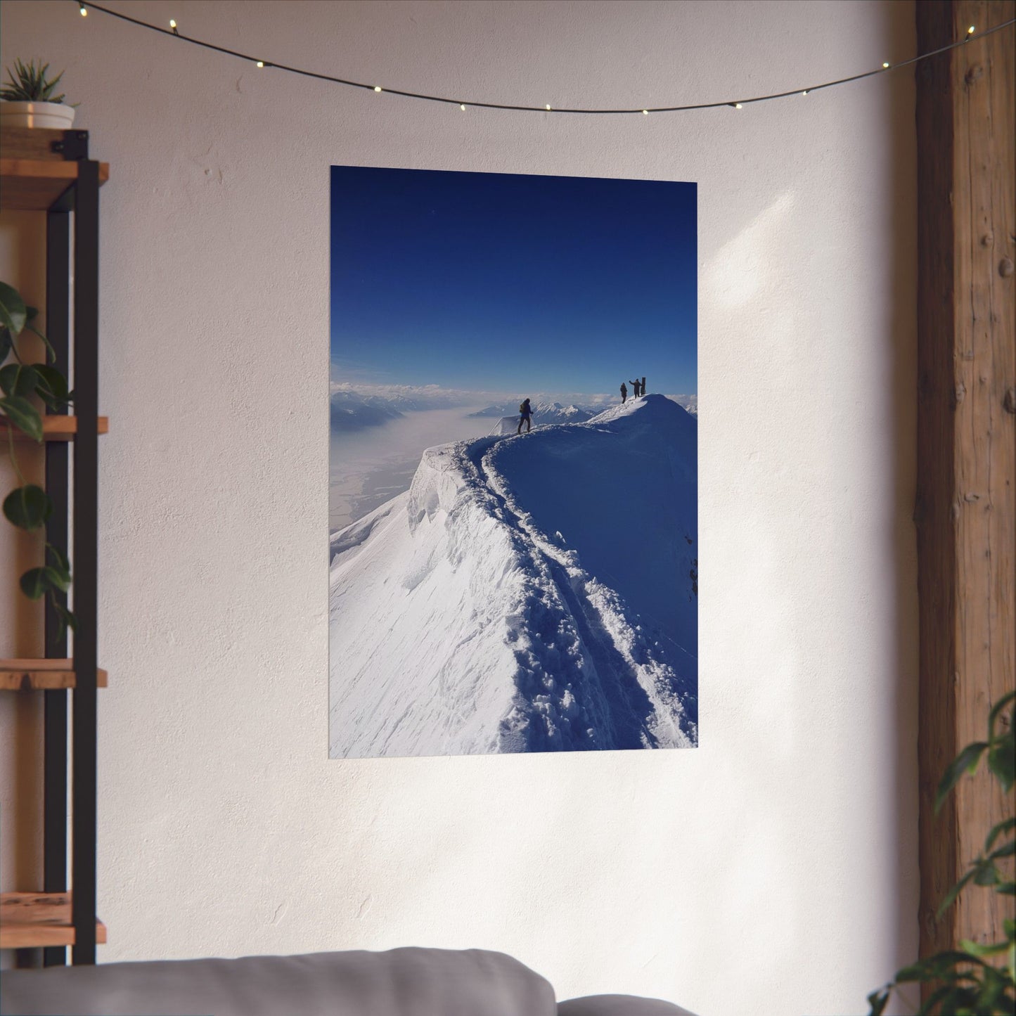 Poster of a snowy mountain landscape on a wall in a room with a plant shelf and sofa.