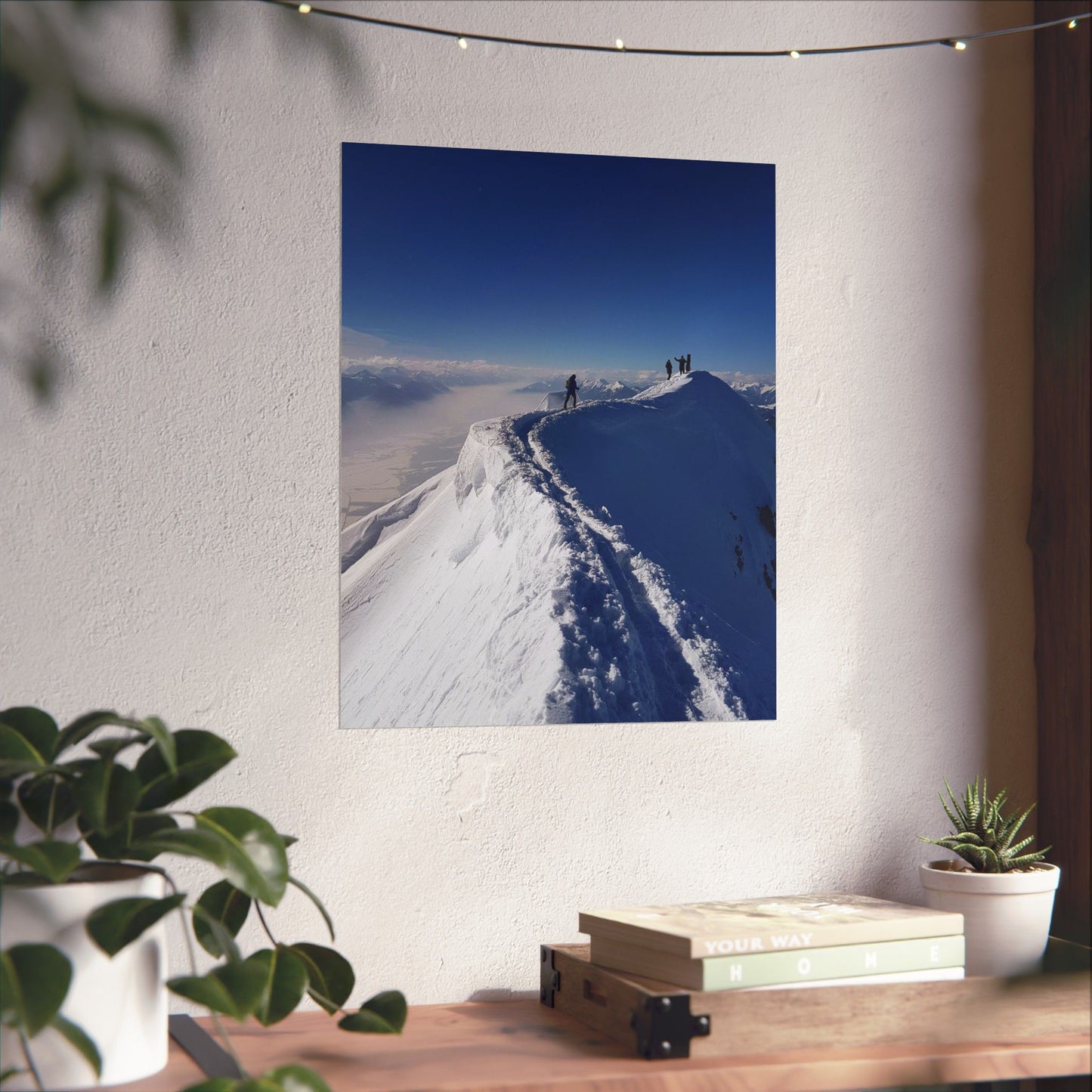 Poster of a snowy mountain landscape on a wall with plants and books below.