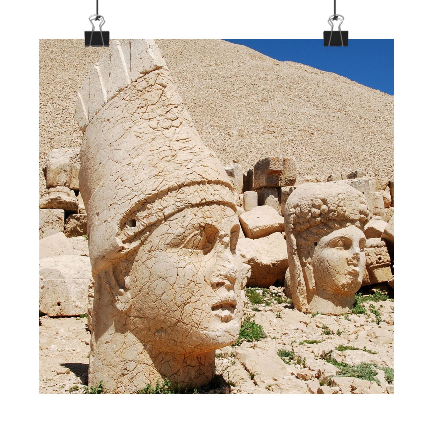 Stone heads of ancient statues on a rocky hillside with blue sky.