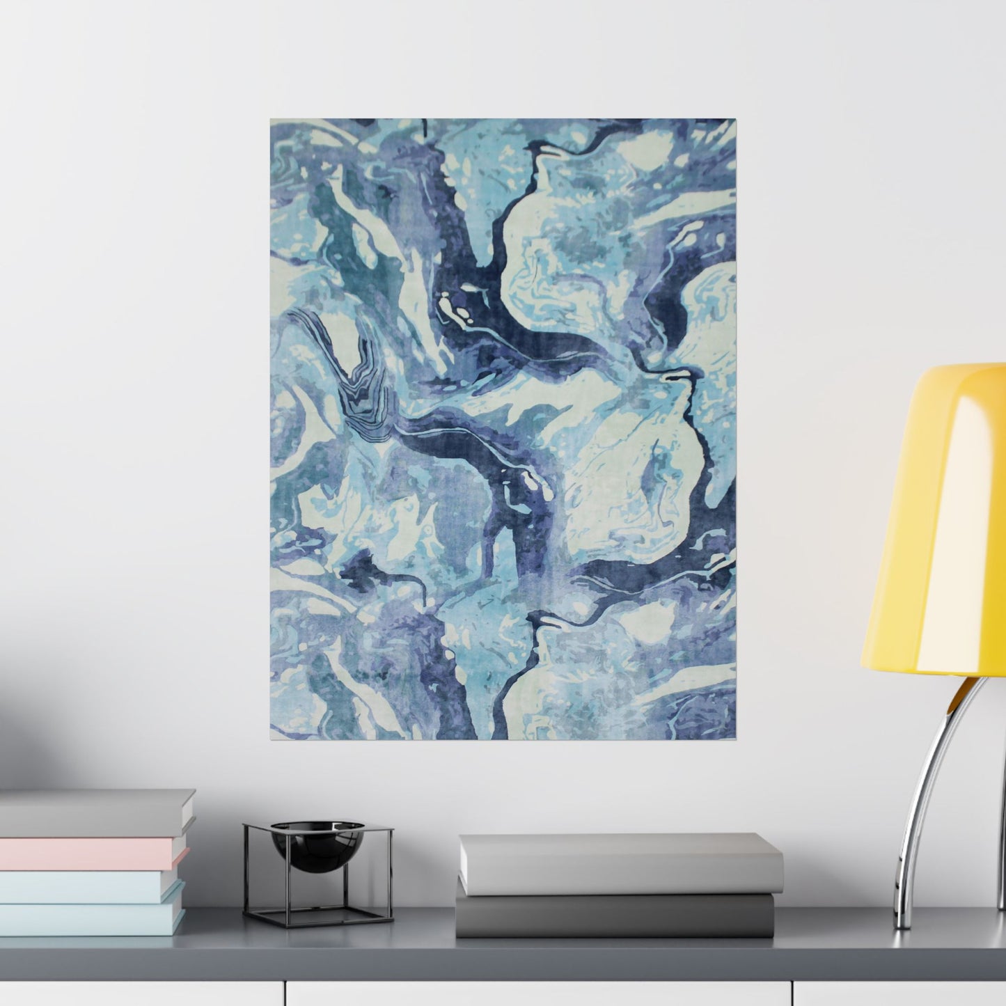 Abstract blue and white painting on a wall above a shelf with books and decor items.