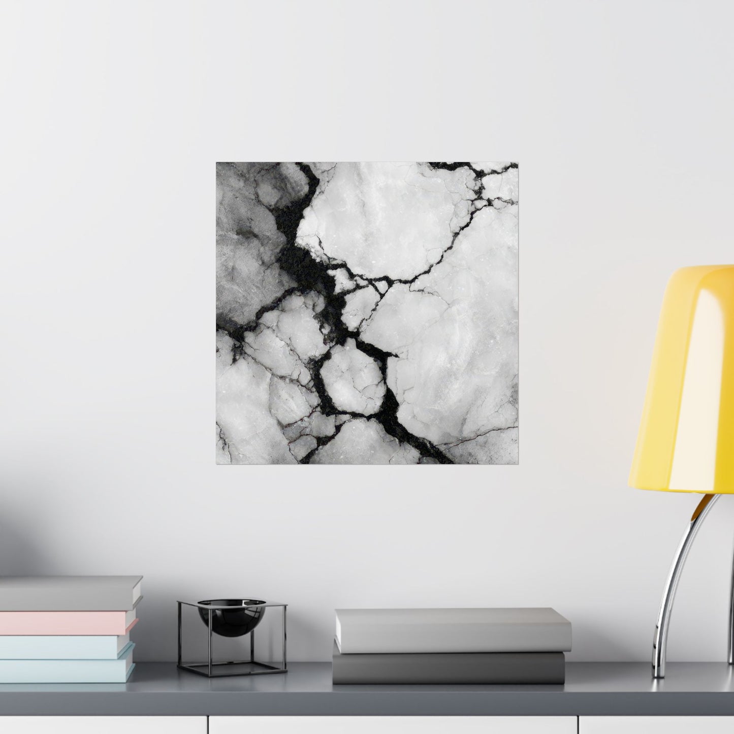 Marble-patterned wall art on a white wall with books and a lamp in the foreground.