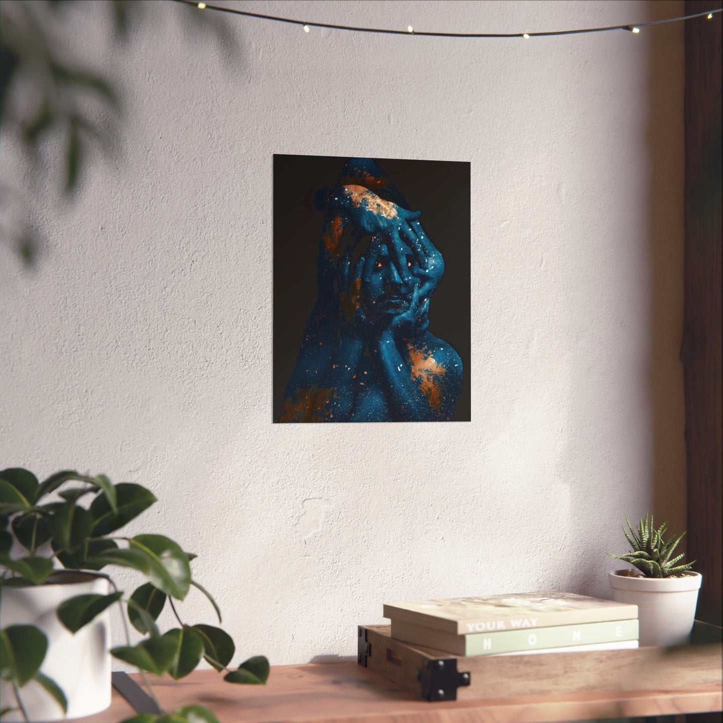 Artistic depiction of a figure with blue and orange colors on a white wall above a wooden surface with plants and books.