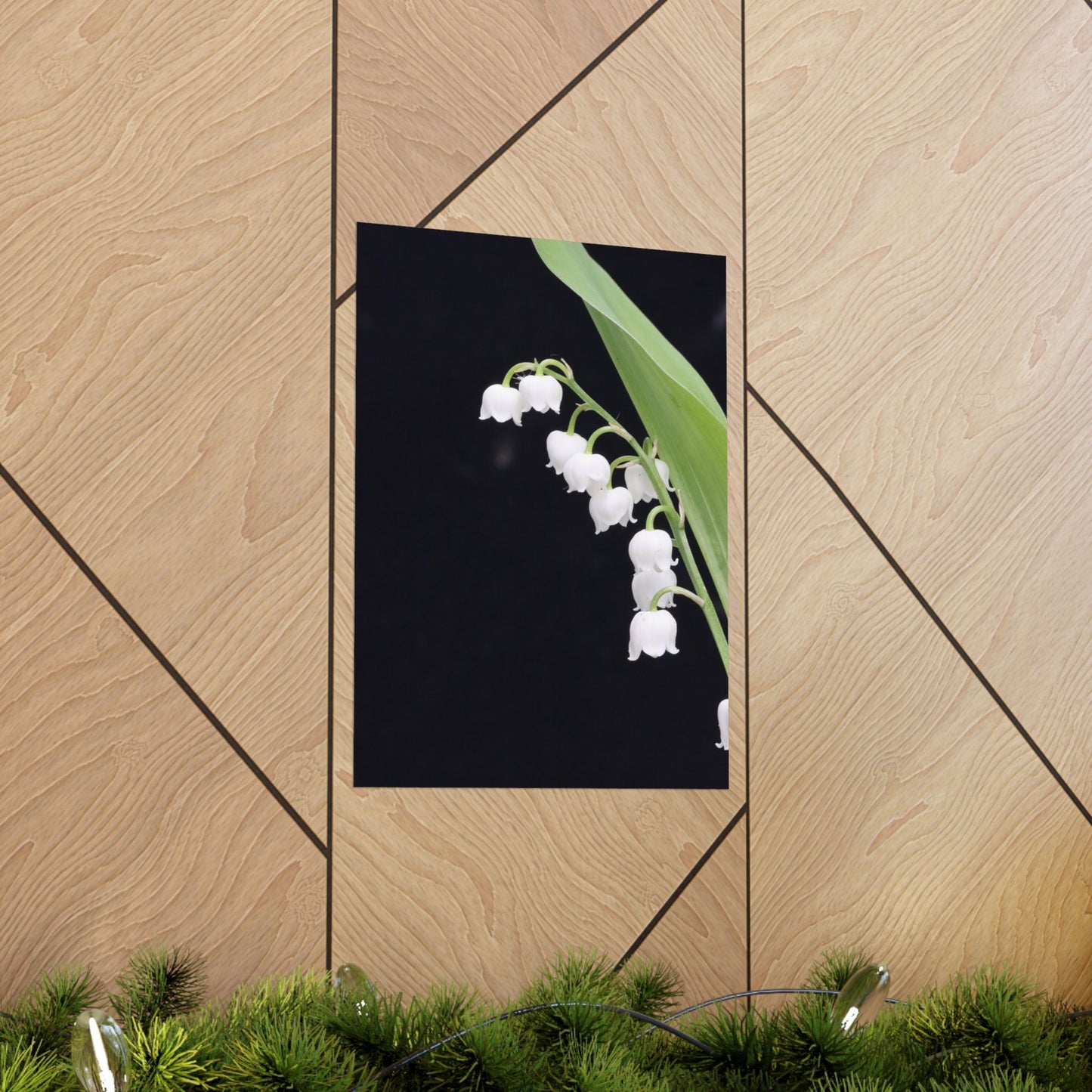 Framed artwork of white flowers on a black background, leaning against a wooden wall.