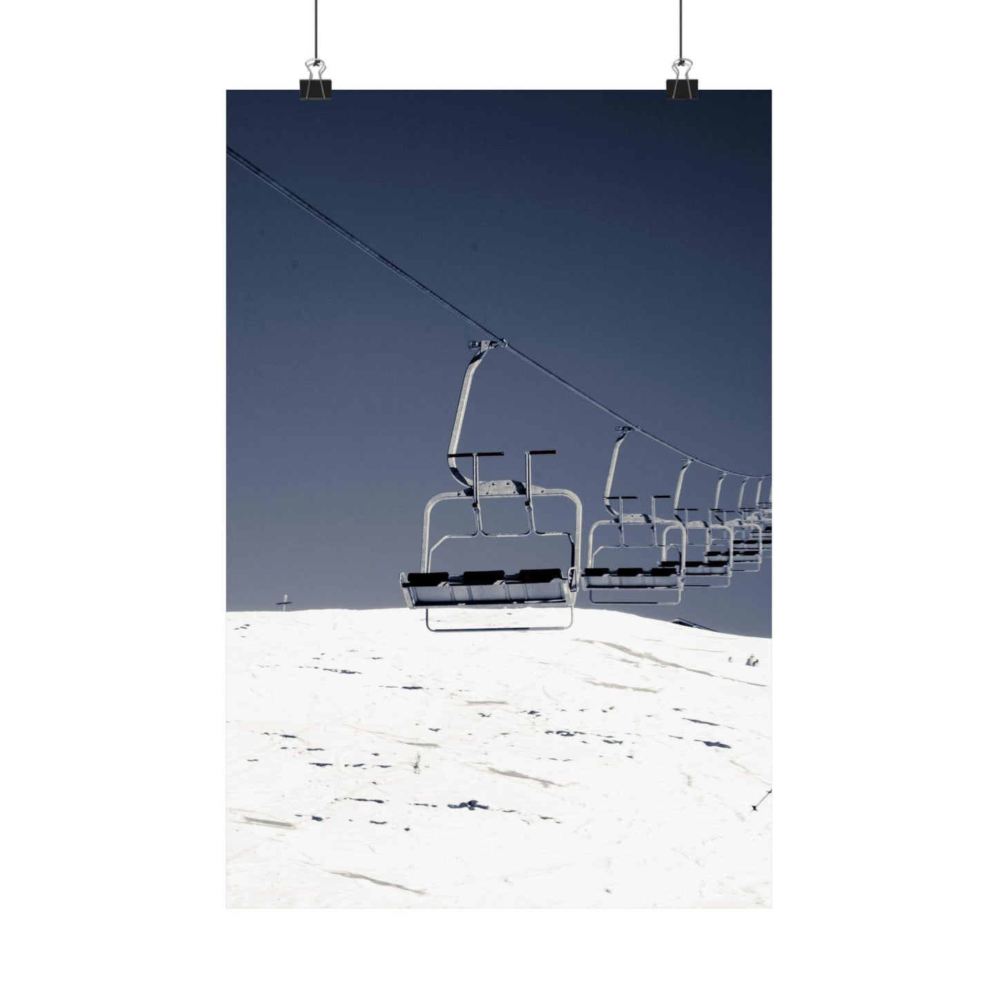 Ski lift chairs on a snowy mountain with clear blue sky