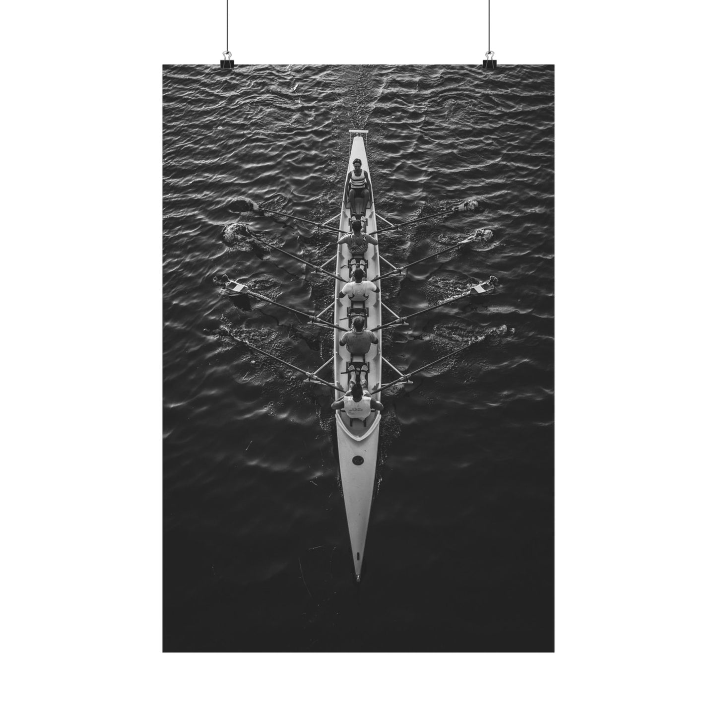 Black and white photograph of a rowing boat with rowers on water