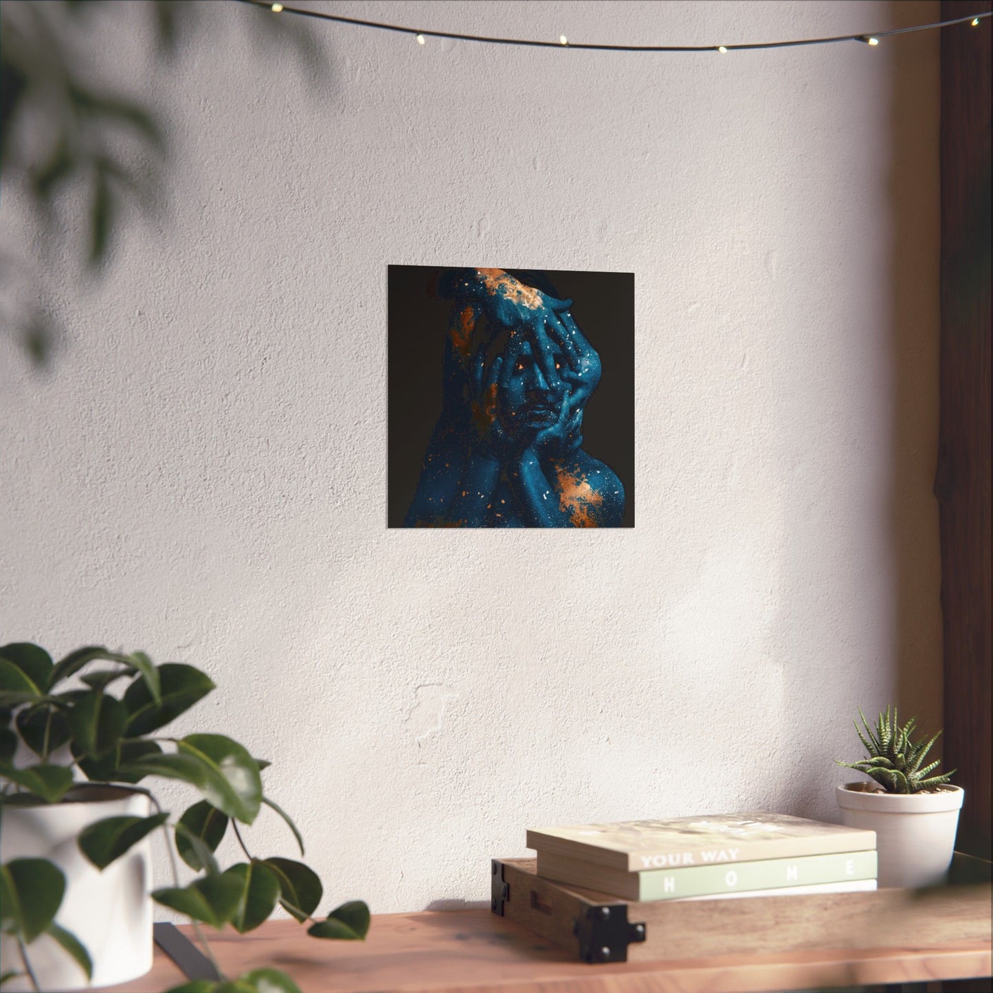 Abstract art piece on a wall above a wooden table with plants and books.