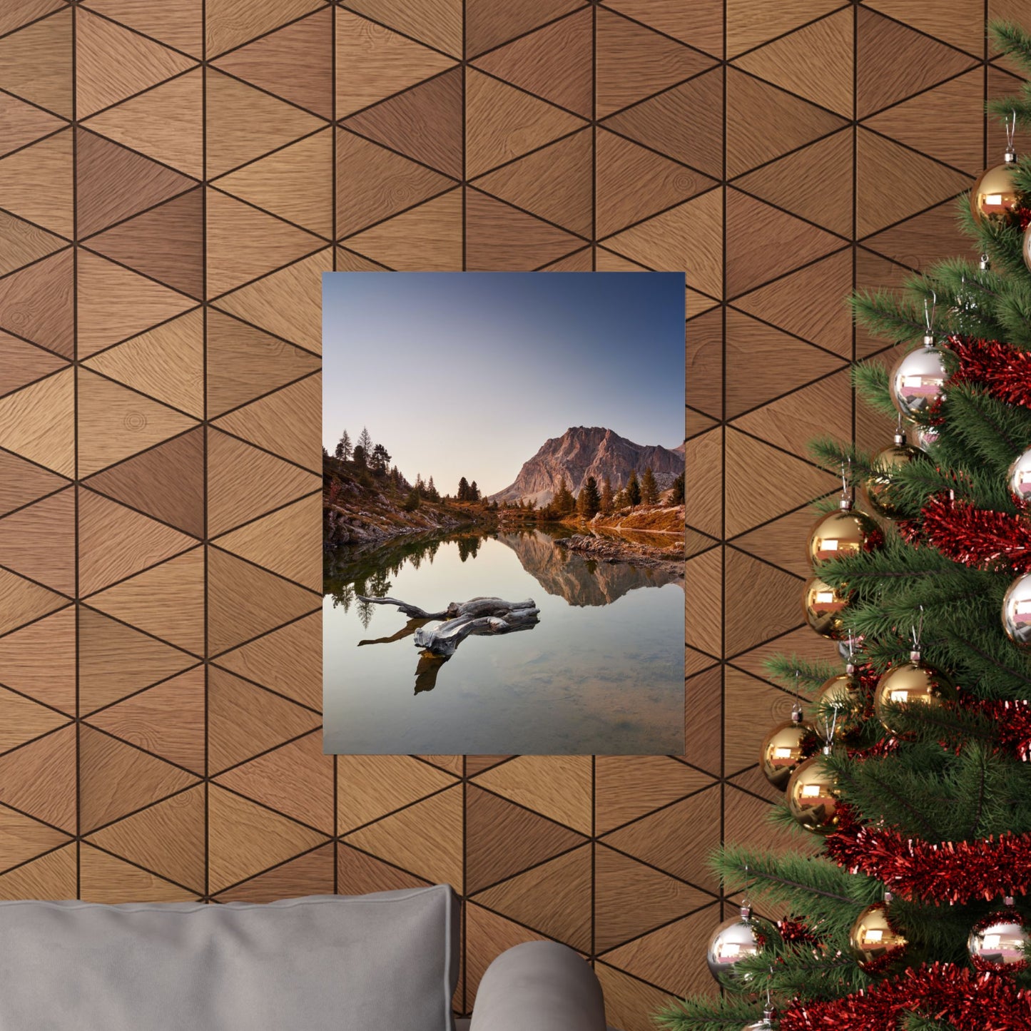 Decorative wall with geometric wood pattern, framed photo of mountain lake, and Christmas tree with ornaments.