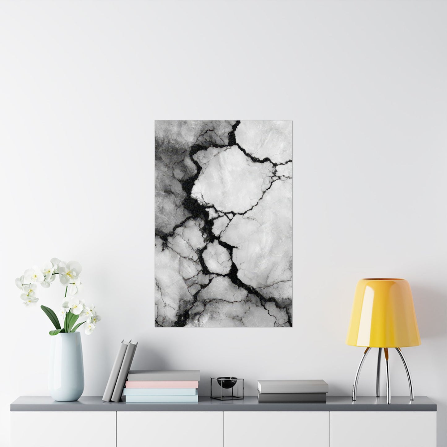 Abstract black and white marble art print on a wall above a shelf with decor items.