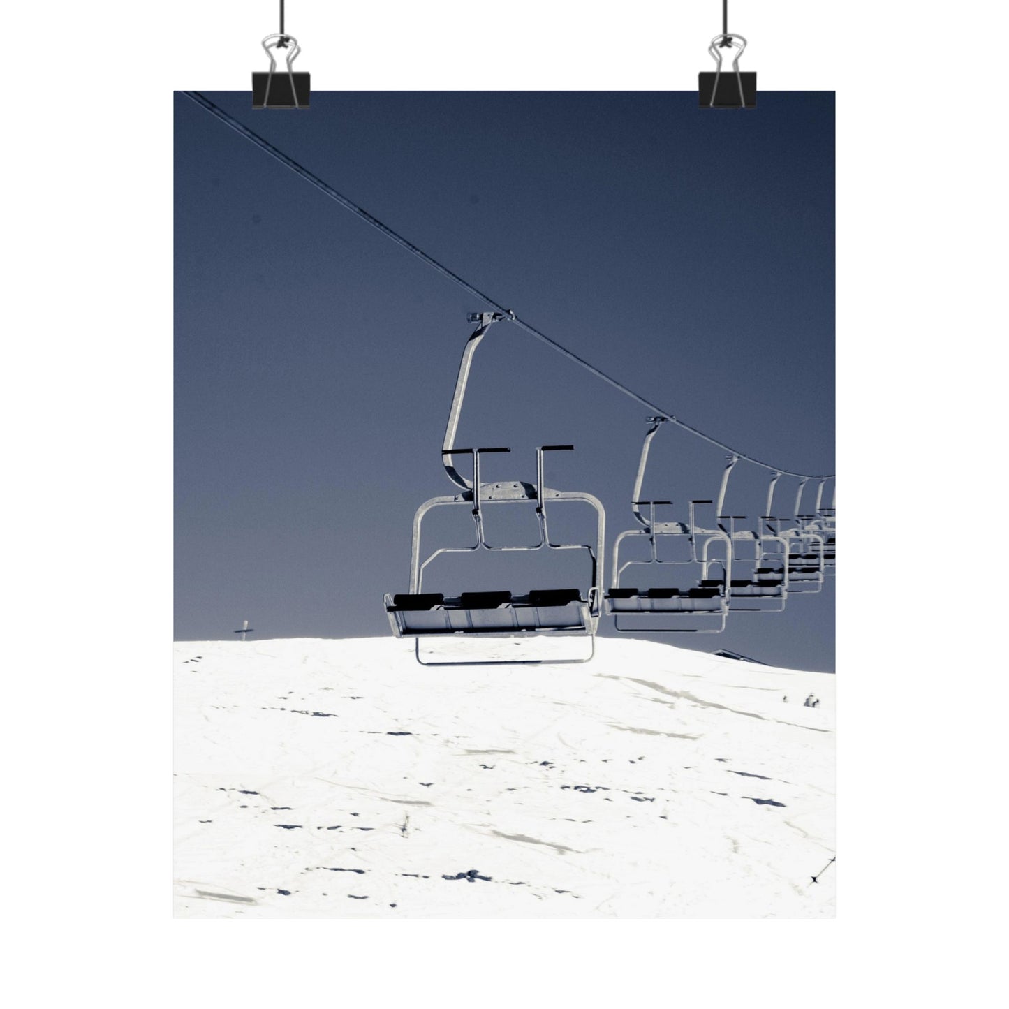Ski lift chairs on a snowy mountain with a clear blue sky