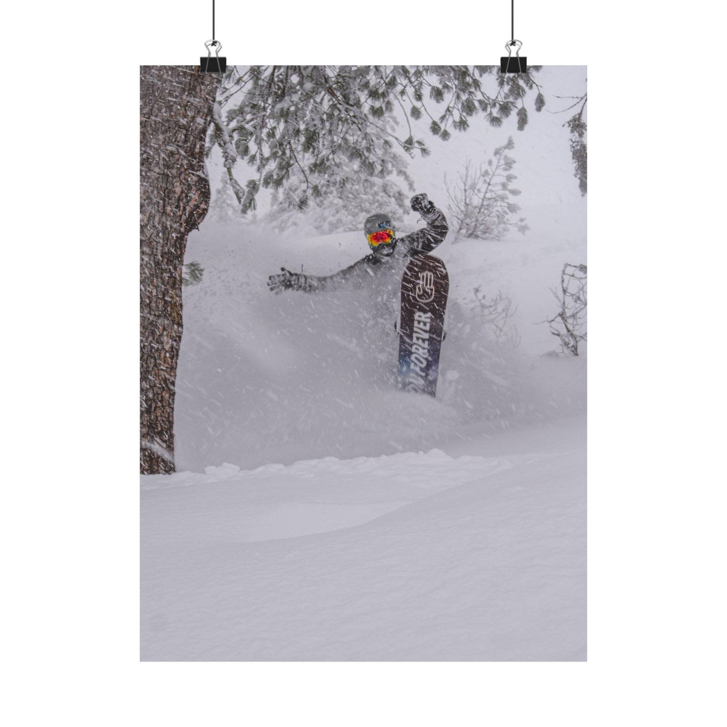 Person snowboarding in a snowy forest with a tree in the foreground