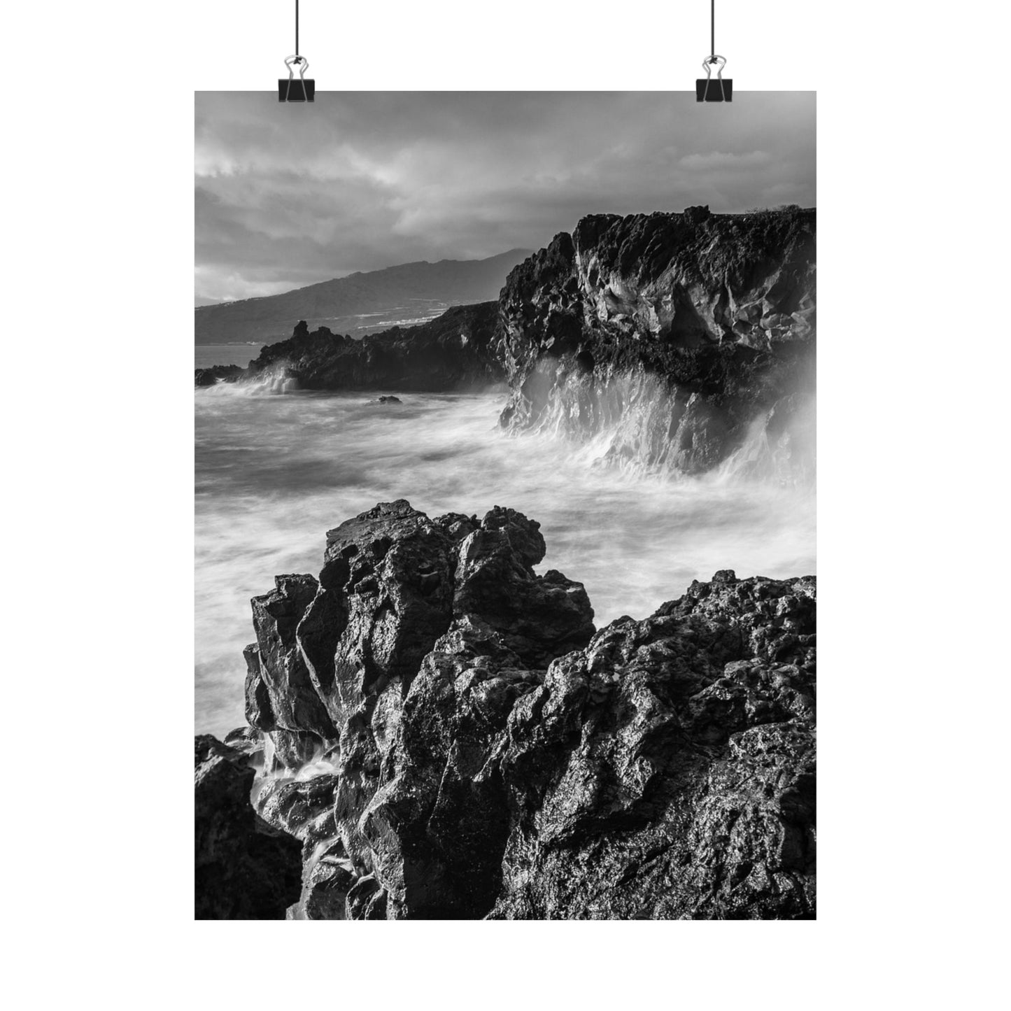 Black and white photograph of rocky coastline with waves crashing against rocks.