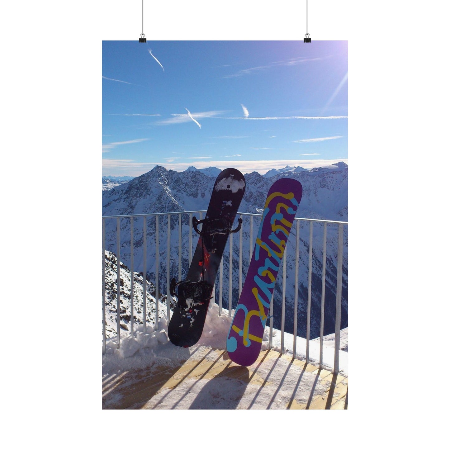 Two snowboards against a mountainous backdrop with a clear blue sky.