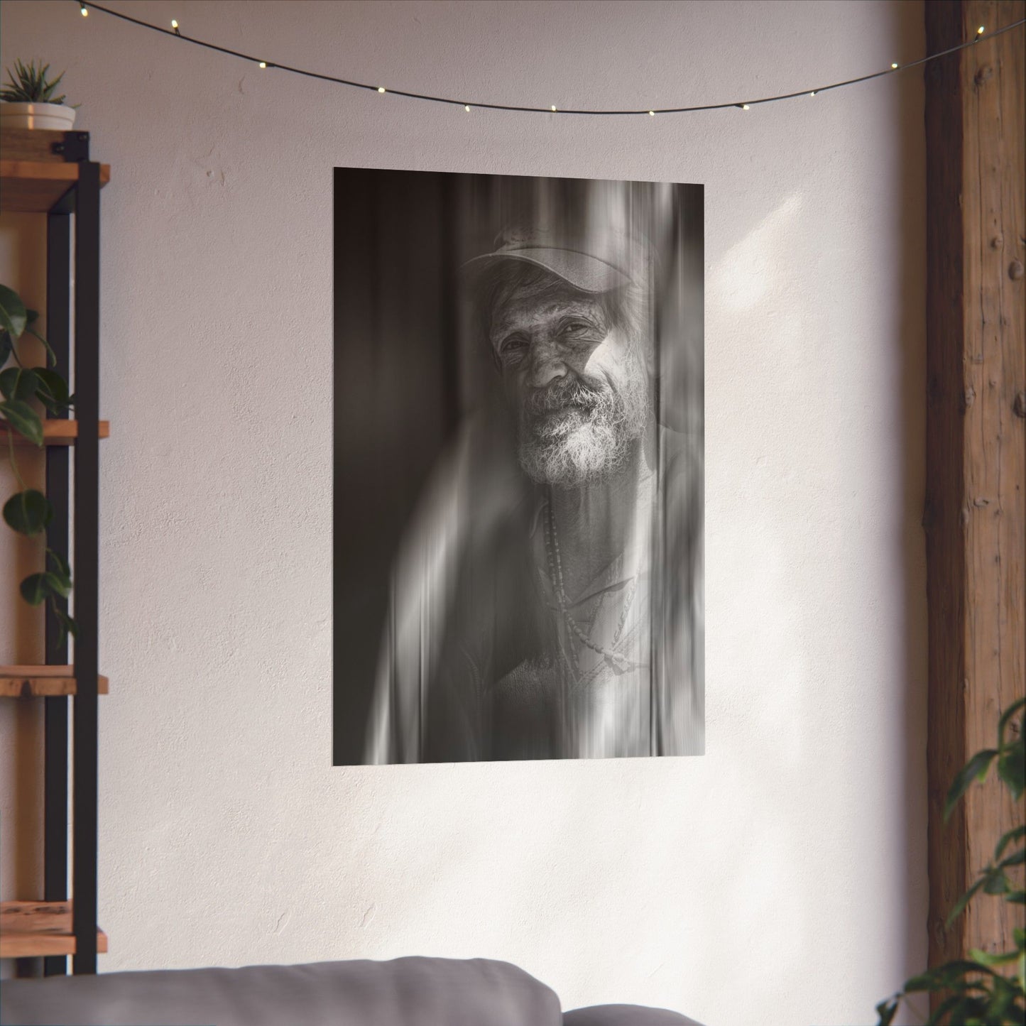 Black and white portrait of a man with a beard hanging on a wall in a room with plants and a shelf.