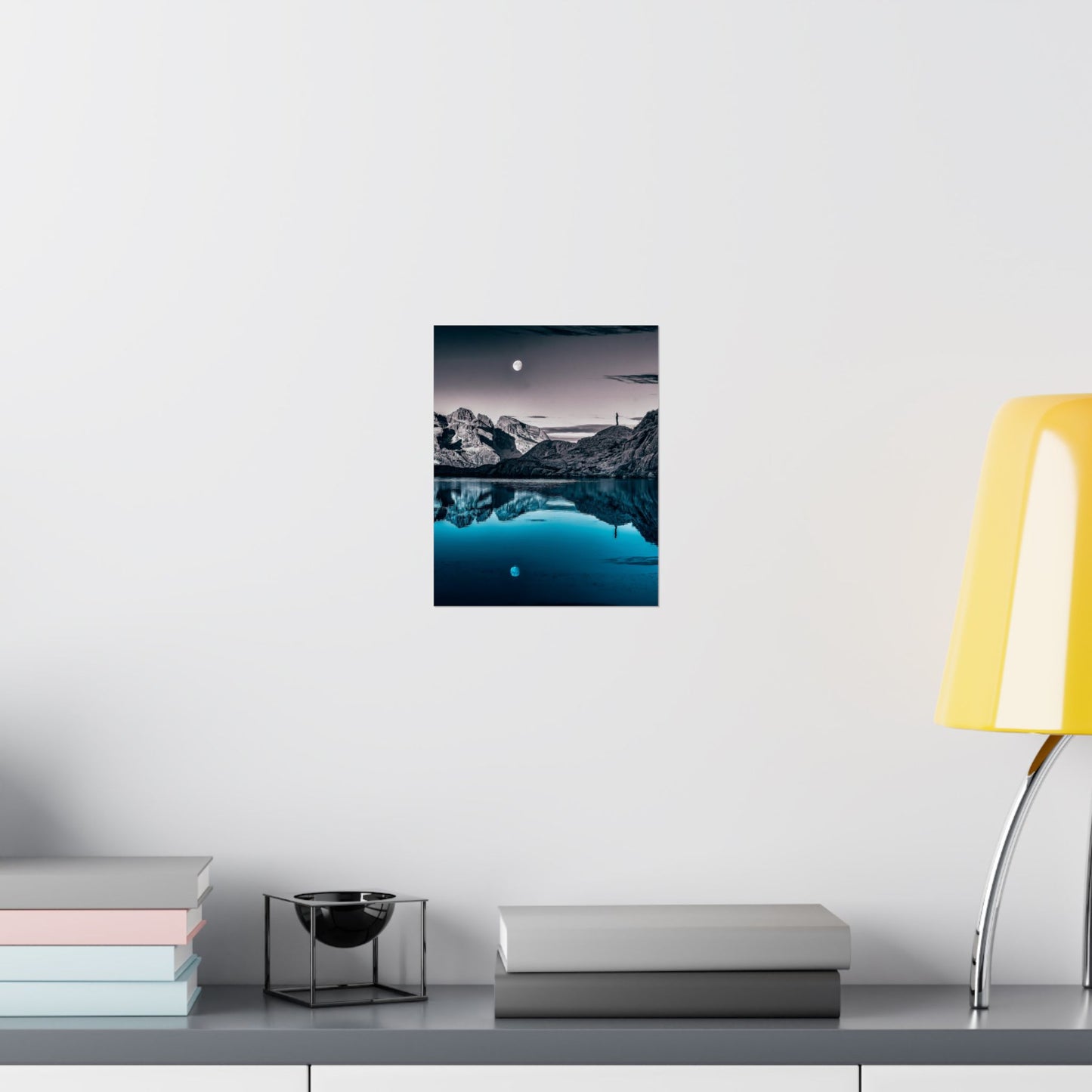 Framed artwork of a coastal scene with rocks and water on a white wall above a shelf.